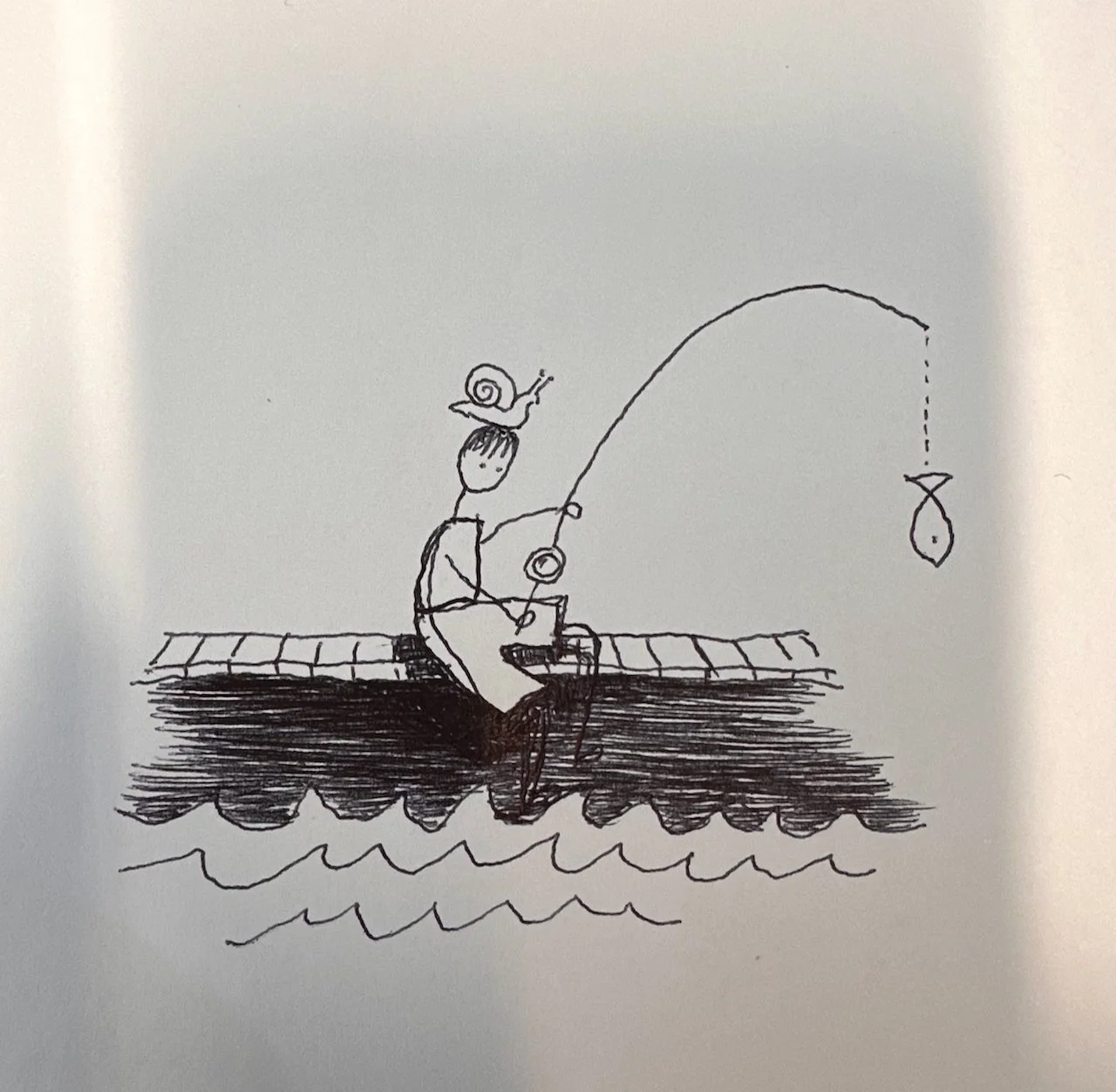 A simple black and white drawing of a person fishing from a dock with a fishing pole. A snail is sitting on the person's head, and the fishing line has a fish hanging from the hook. The person is sitting cross-legged, with water beneath and a dock in