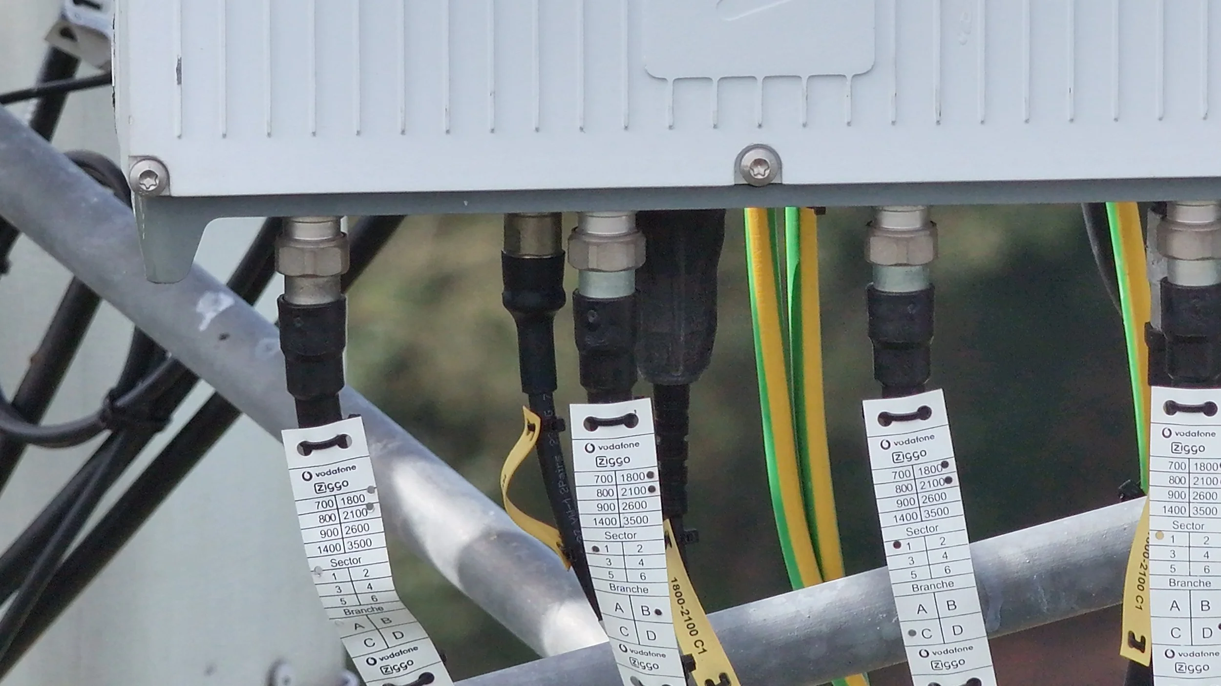 Meerdere kabels met stickers, aangesloten op een elektronische besturingseenheid.
