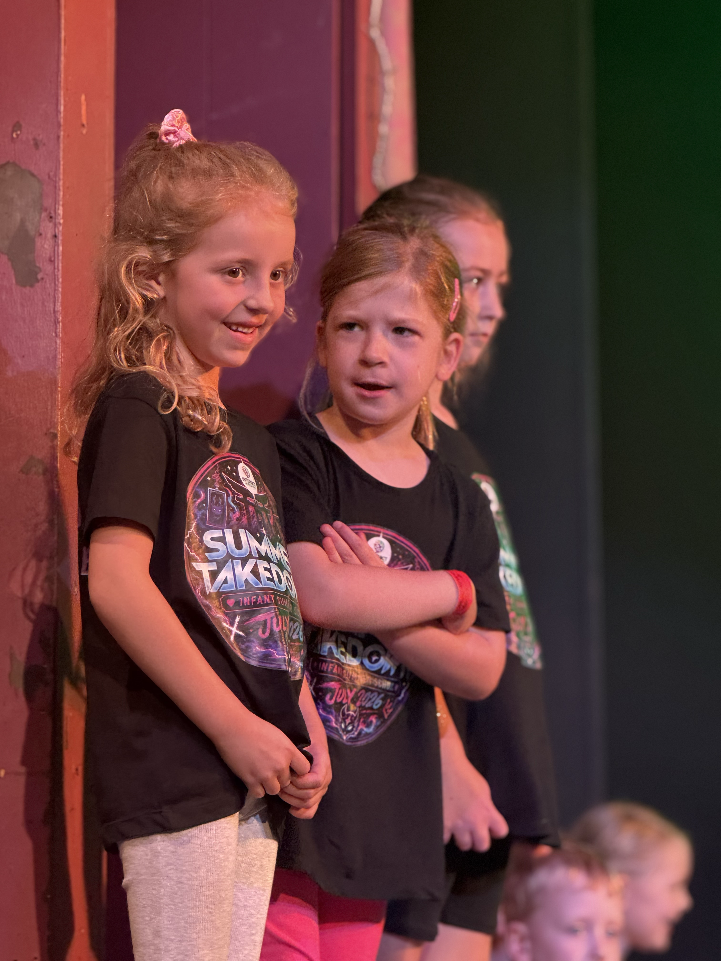 Children standing in a line, watching an event or performance with focused expressions.