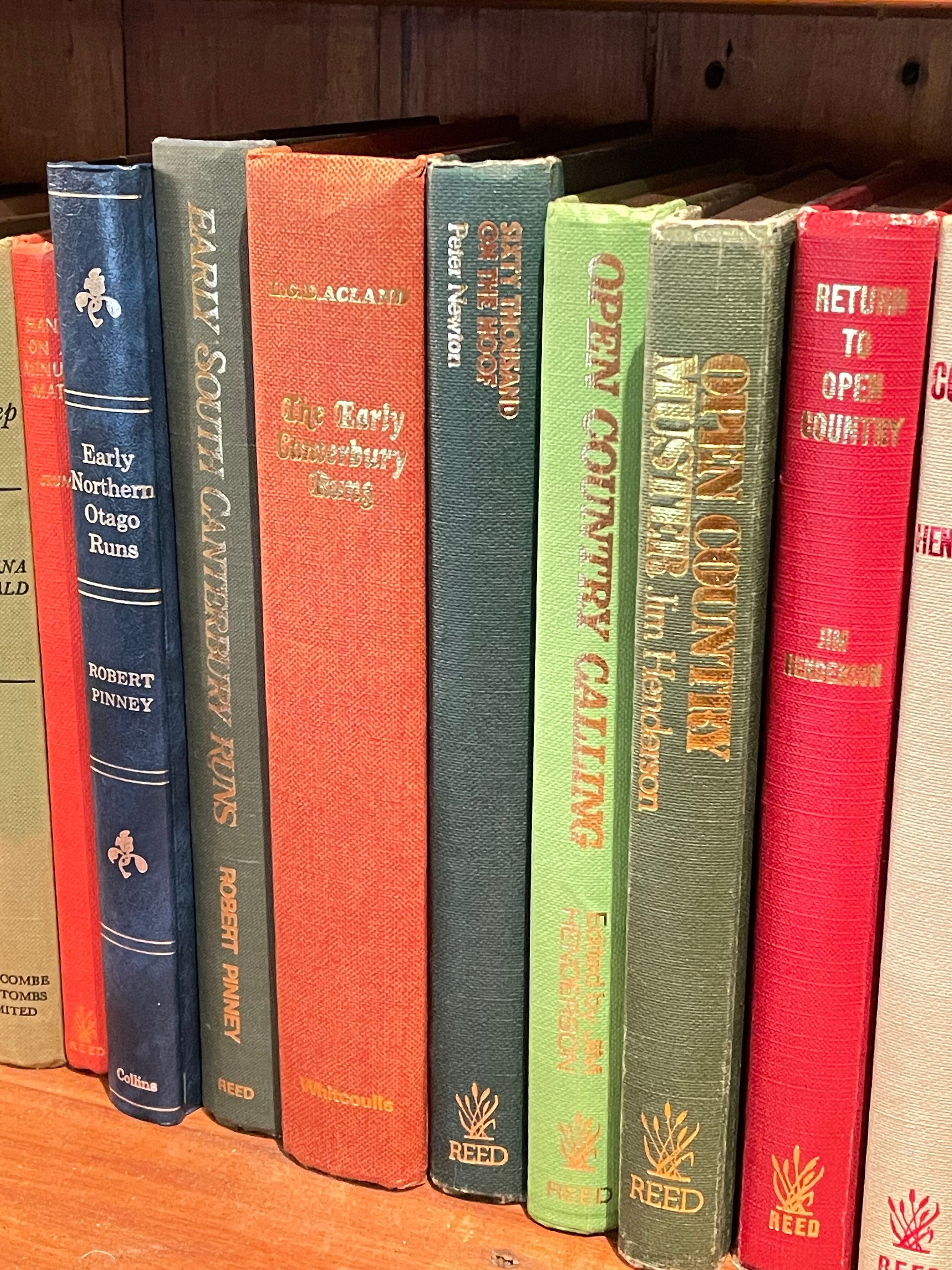 A row of hardcover books with colorful covers on a wooden shelf.