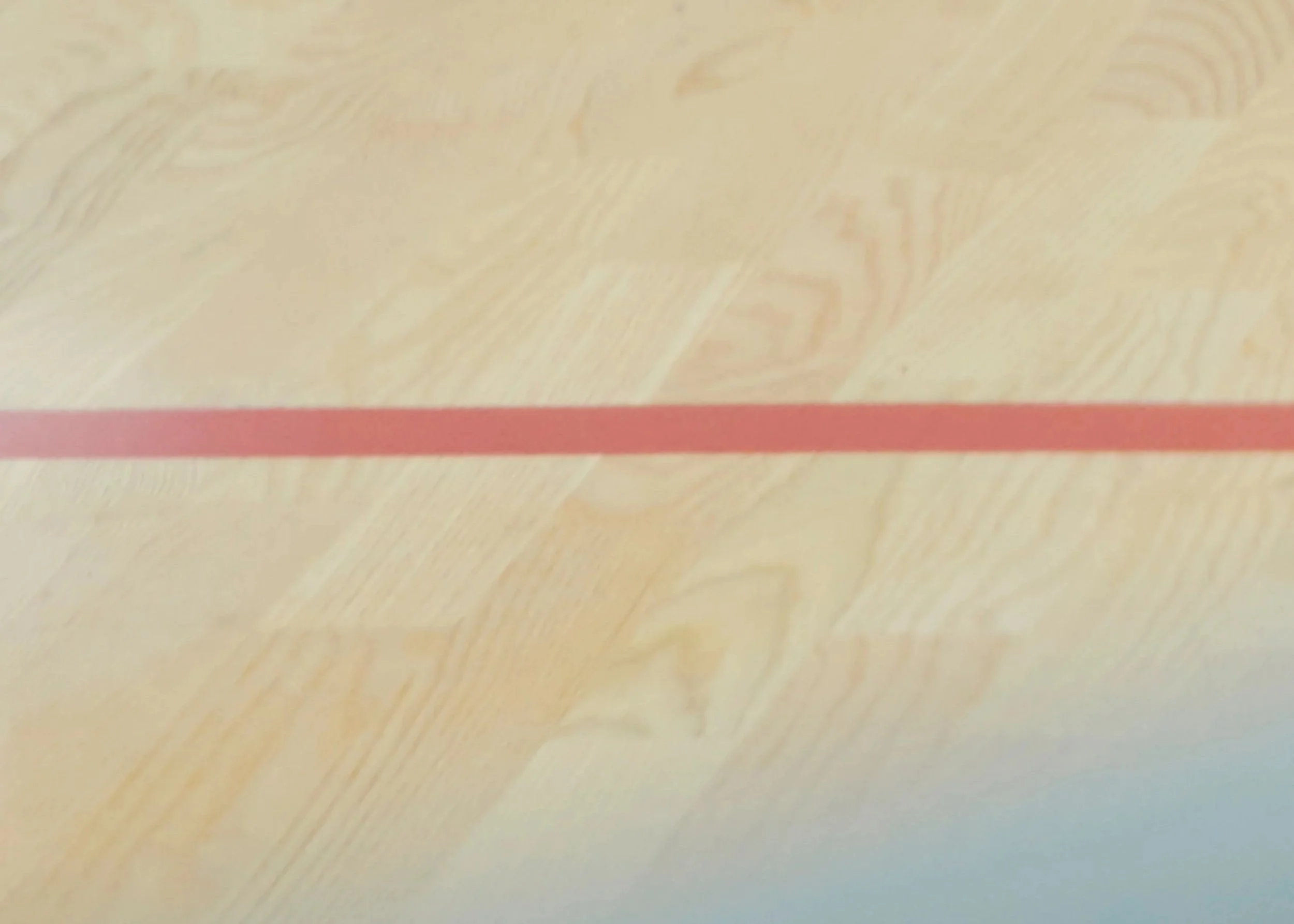Light wood surface with a horizontal red stripe across the center