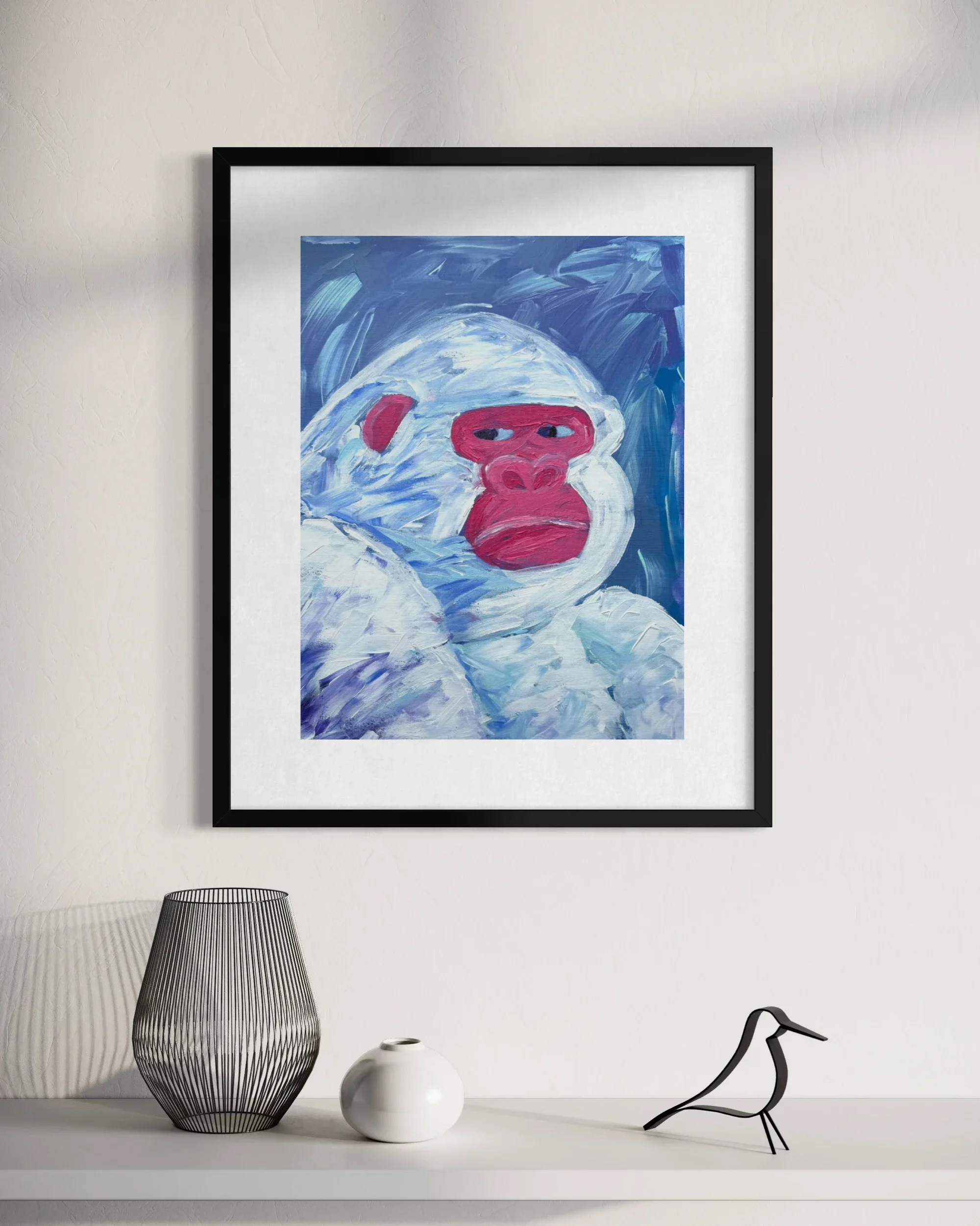 Minimalist interior decor with a framed abstract painting, a black wire vase, a small white ceramic vase, and a black bird sculpture on a white shelf against a white wall.