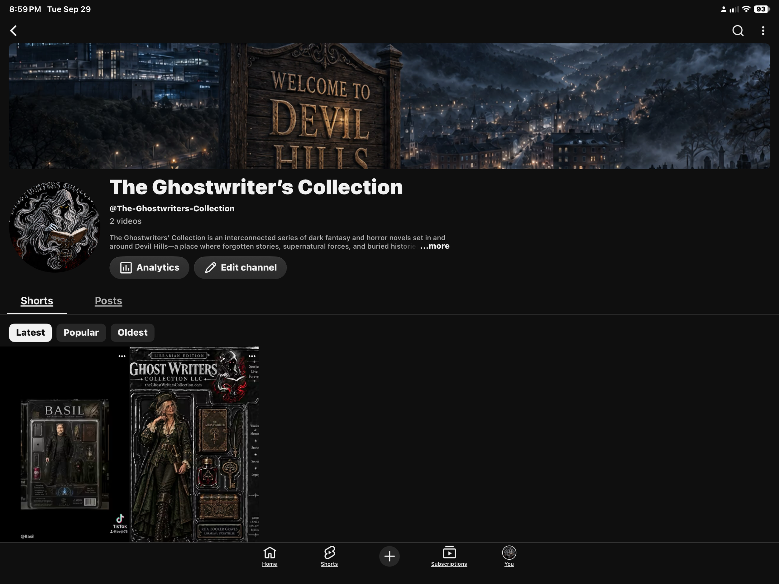 Phone screen showing a YouTube channel page titled 'The Ghostwriter's Collection' with a dark fantasy-themed banner. The banner depicts a foggy mountain town at night with a wooden sign reading 'Welcome to Devil Hills.' The profile picture features a black and white drawing of a ghostly figure with yellow eyes reading a book. The channel description mentions dark fantasy and horror novels set around Devil Hills.
