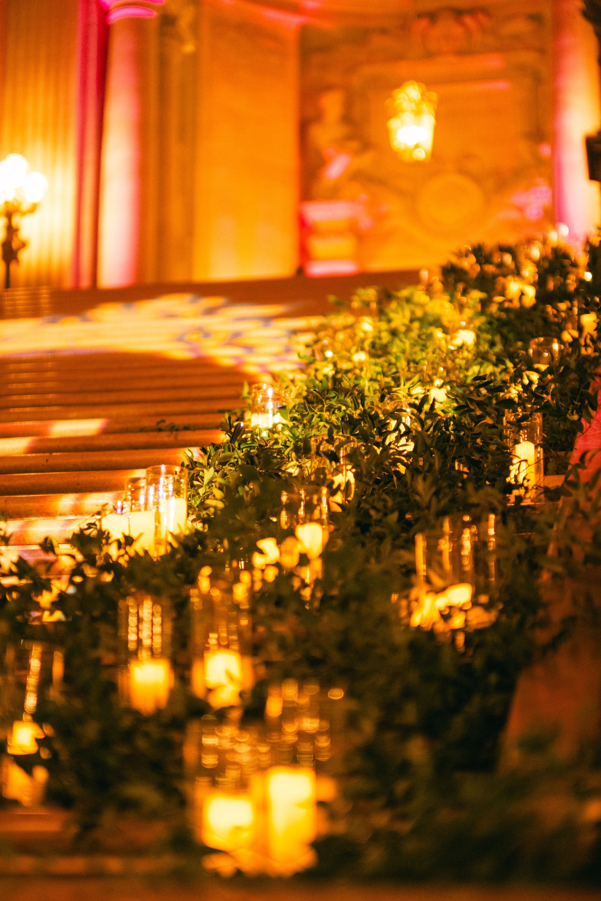 An indoor event space or stage with warm lighting, candles, and floral arrangements.
