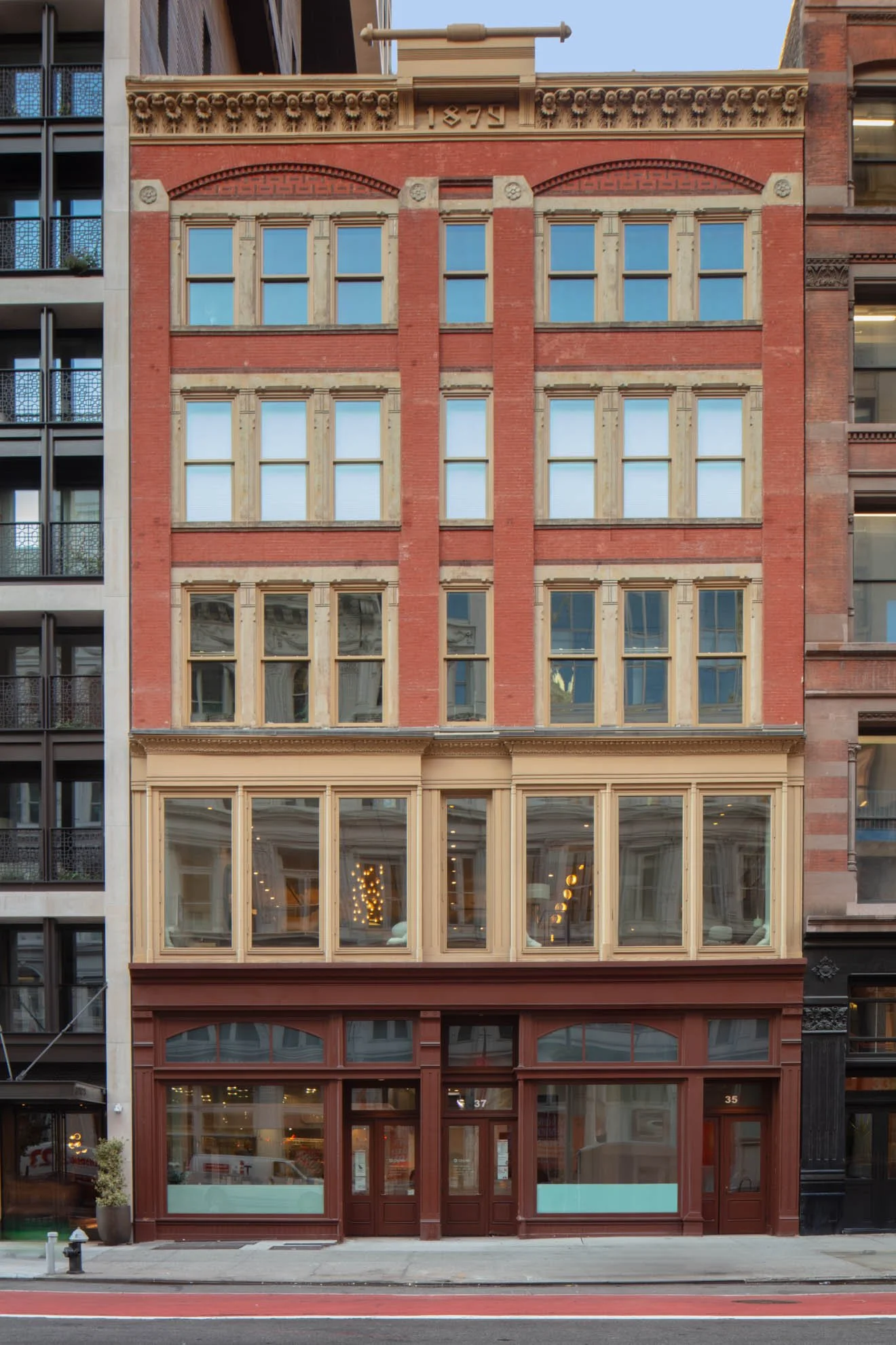 P826 Historic facade of a five-story building featuring red bricks and stone window framing in a soft brown color and a commercial property on the ground level
