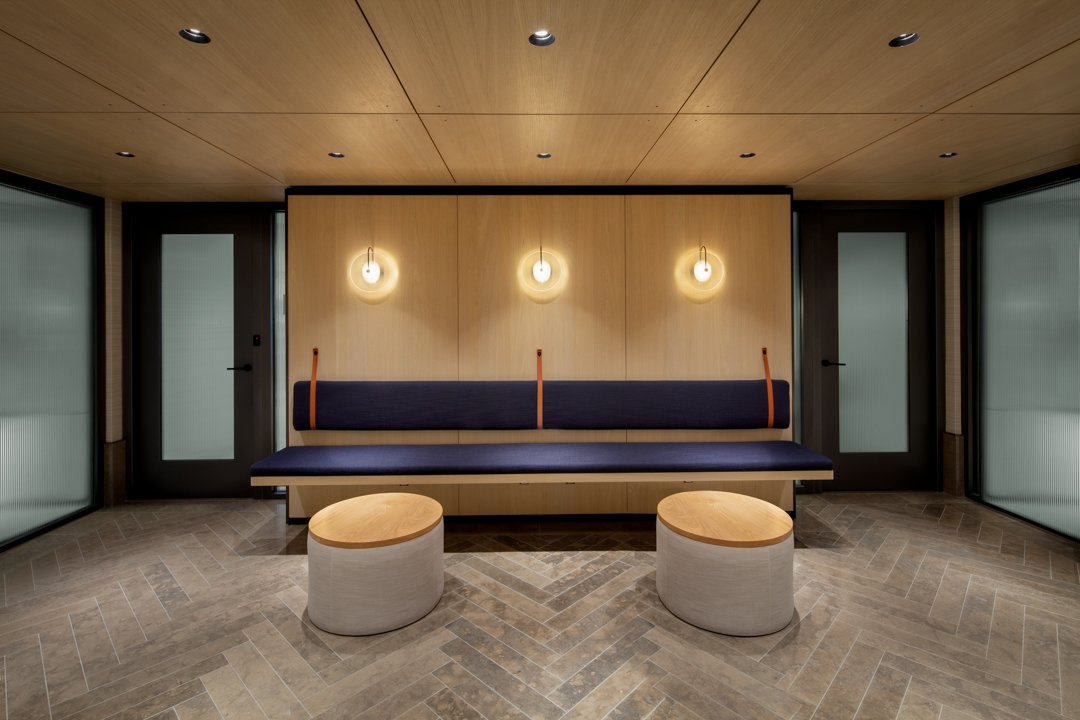 P800 common area with blue upholstered bench with orange back straps on a wood-paneled wall with 