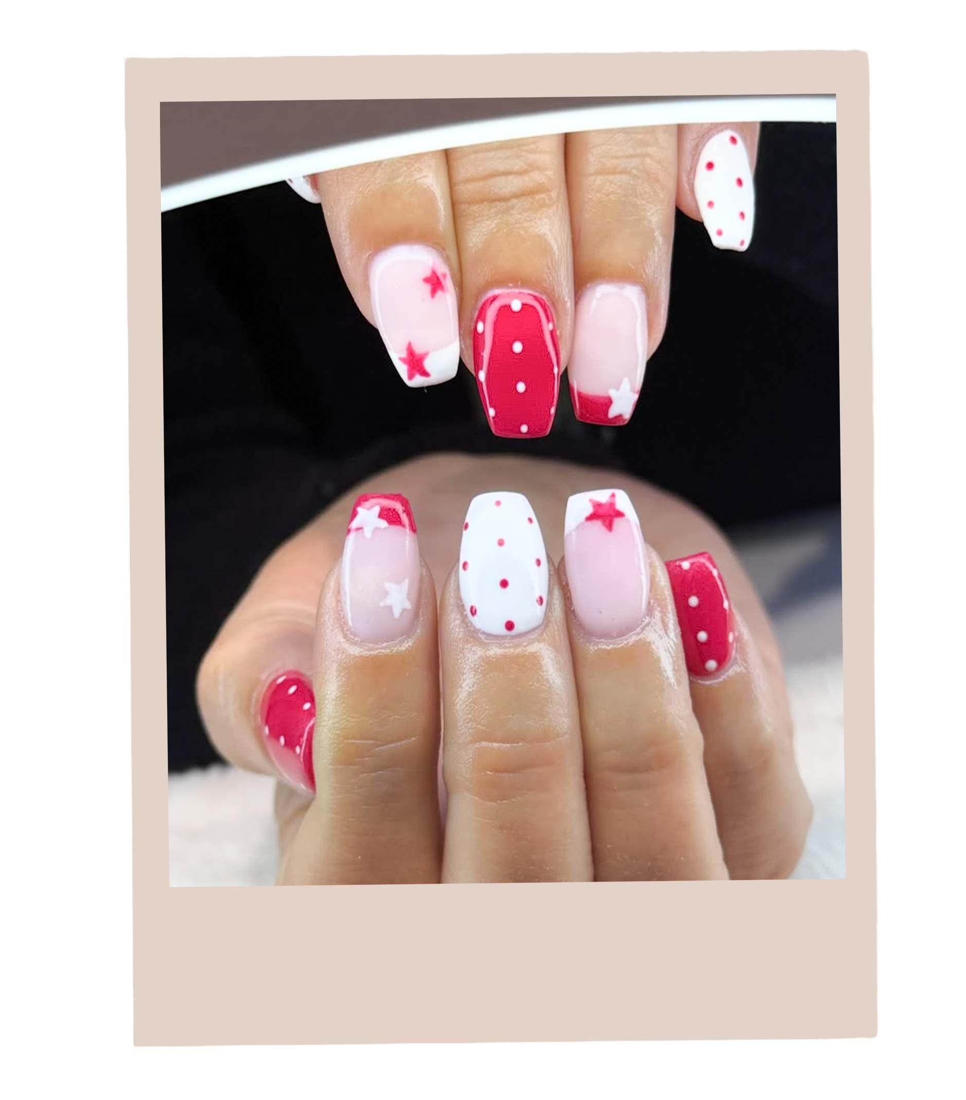 Close-up of a hand with decorated Christmas-themed nail art featuring red and white colors, stars, polka dots, and snowflake patterns.