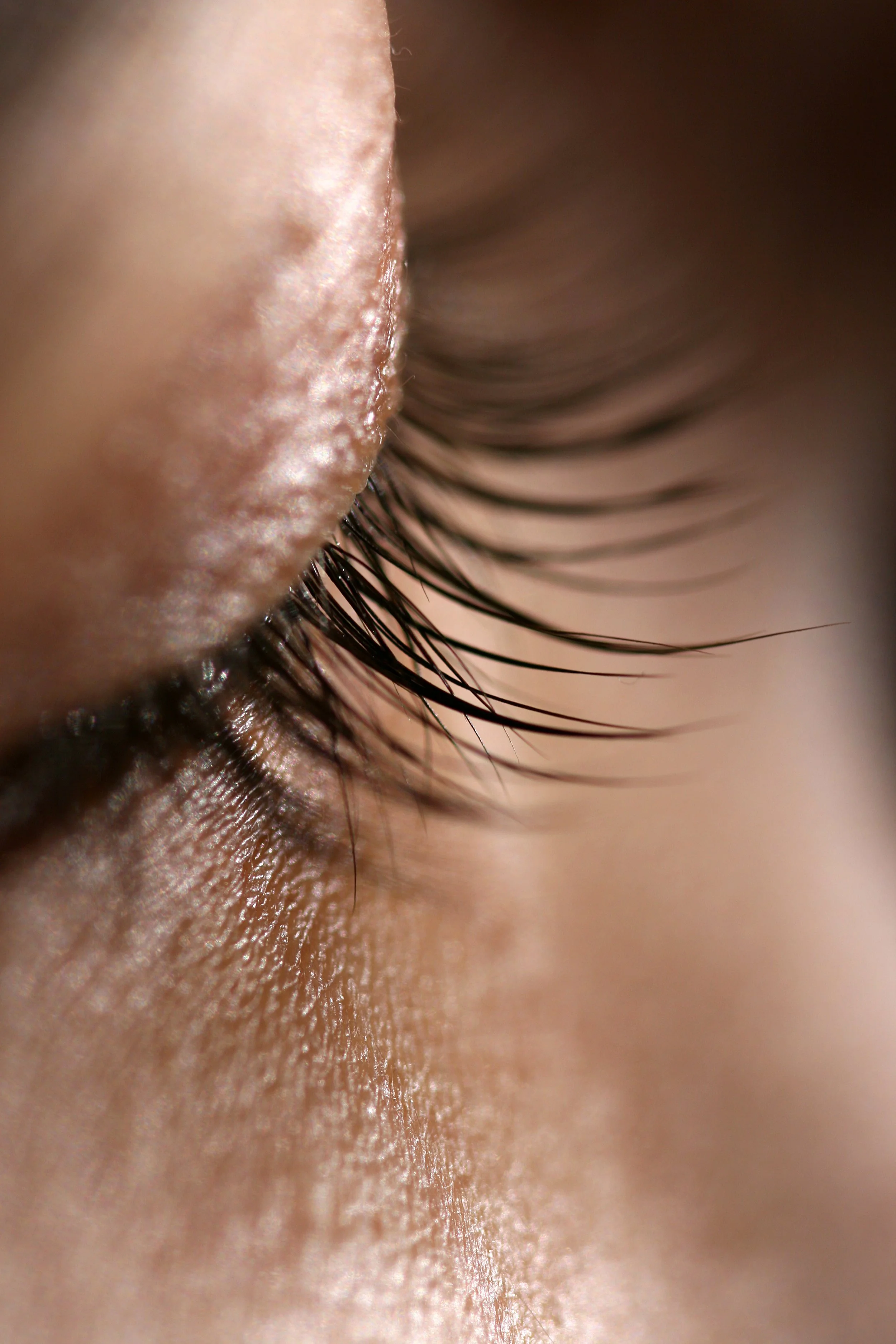 Close-up photograph of a person's closed eye, showing eyelashes and skin detail.