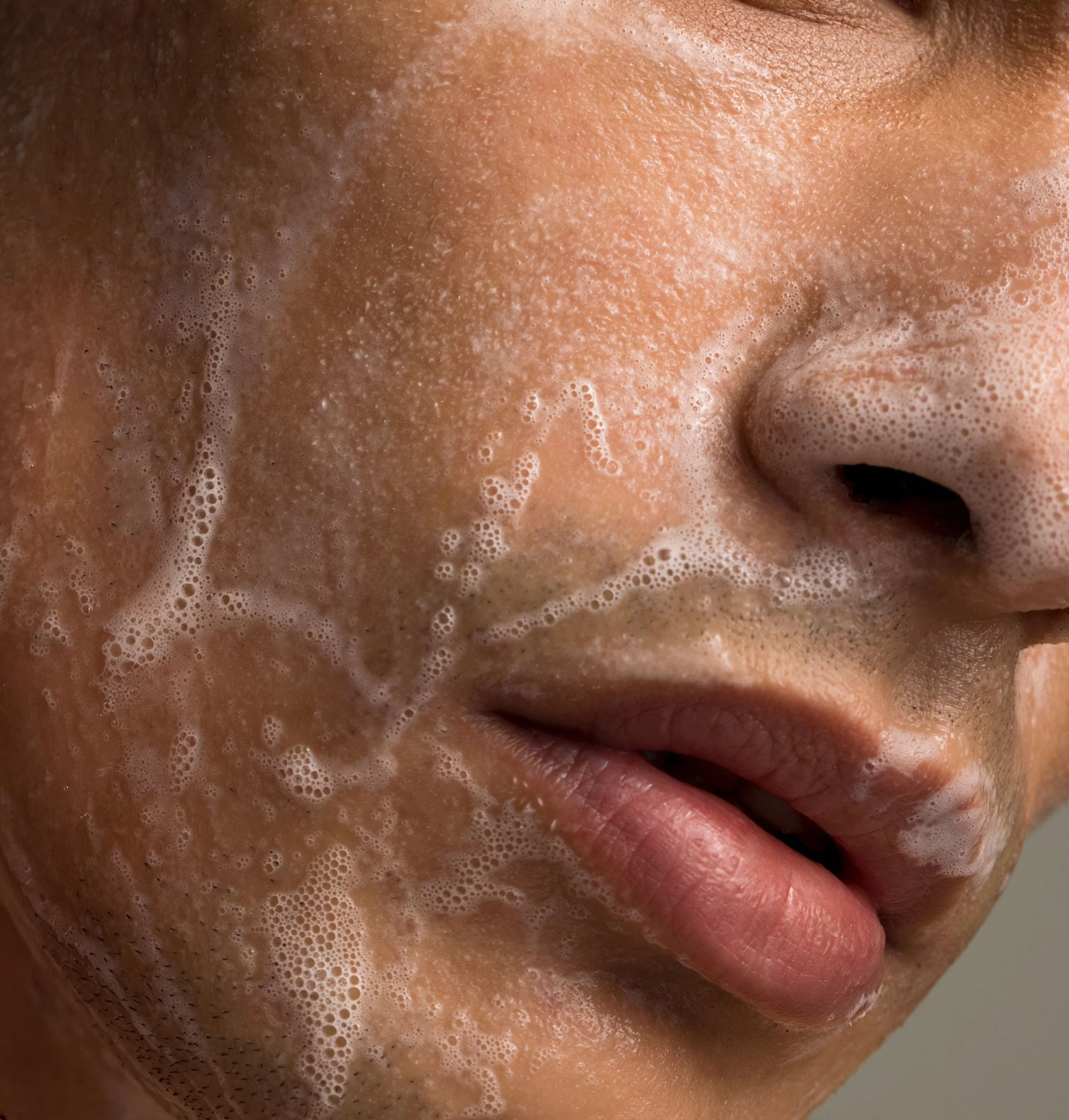 Close-up of a person's face with soap bubbles on the skin, nose, and lips.