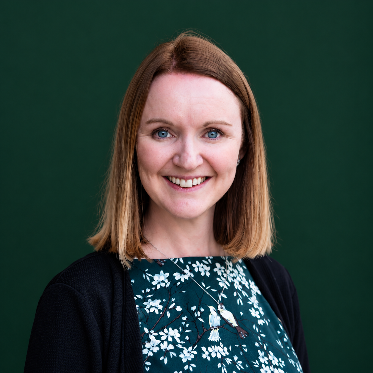 Headshot of smiling female tutor with long braids wearing a lanyard.