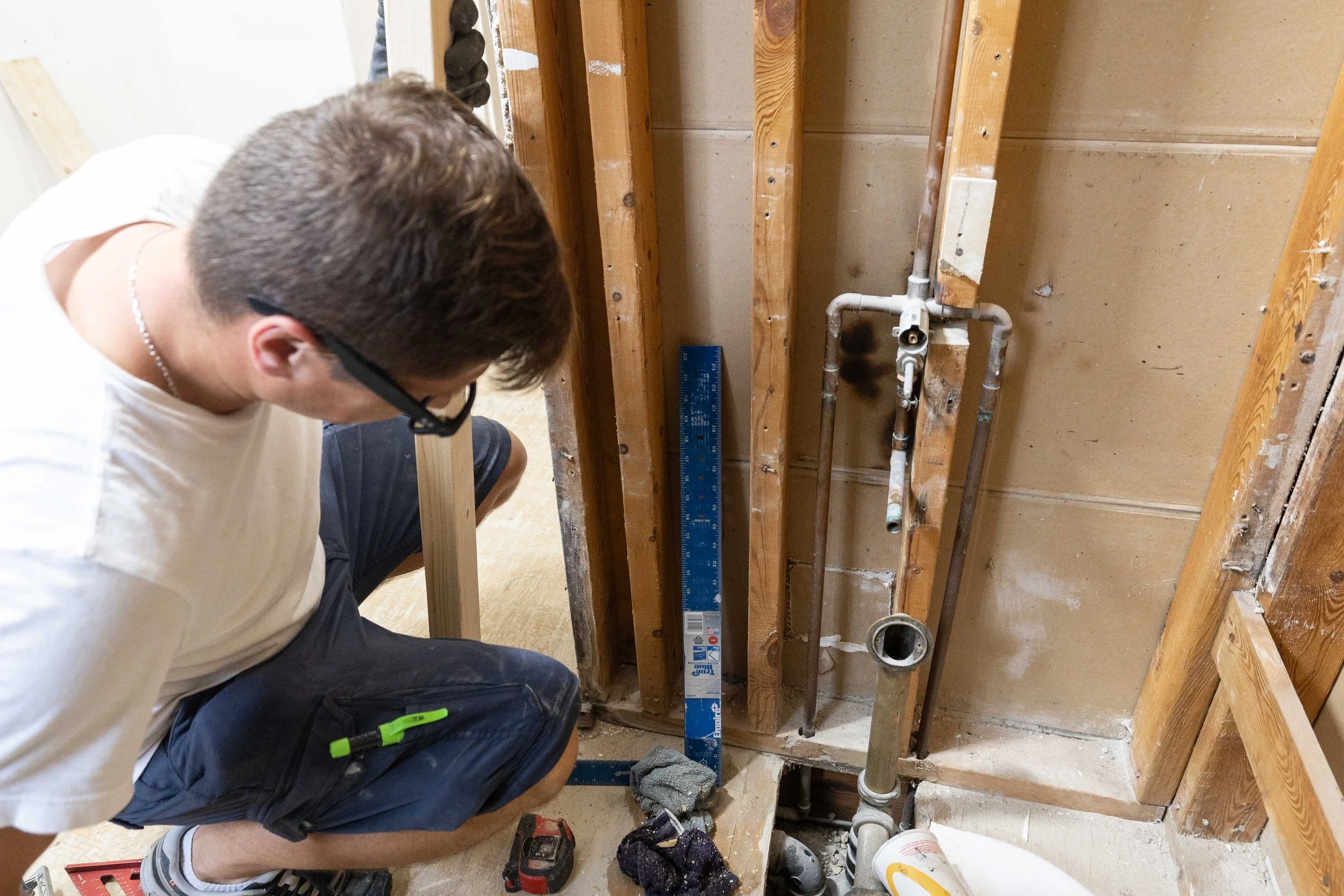 Person installing plumbing pipes inside a wall frame during home renovation.