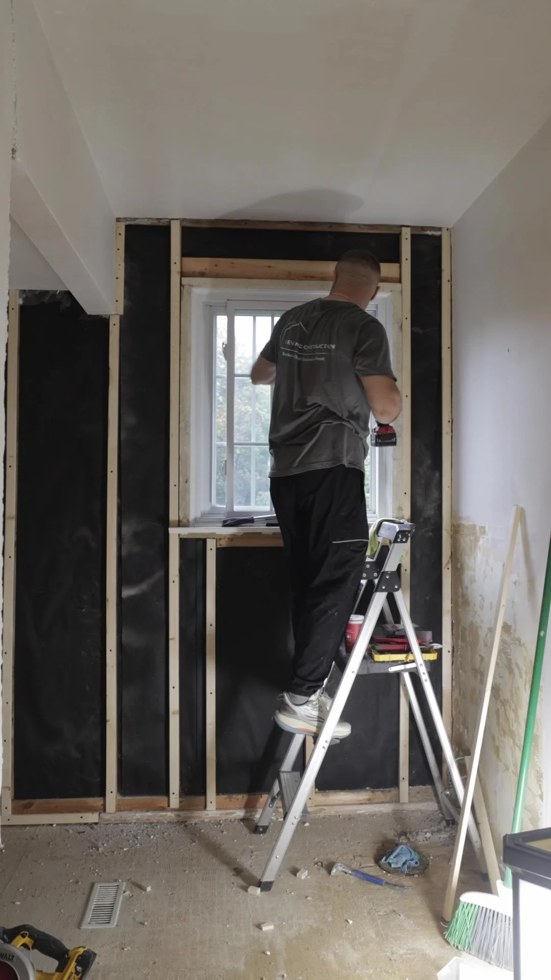 Levand Construction crew member on a ladder adding new wood framing around the window wall of a bathroom under renovation in Etobicoke
