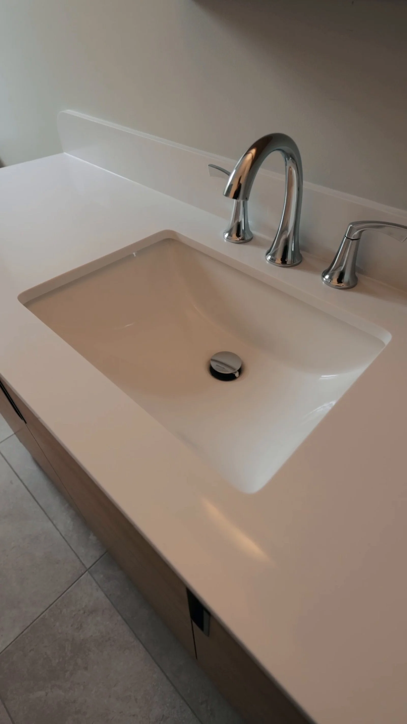 New chrome faucet and white sink set into the countertop of a new bathroom vanity