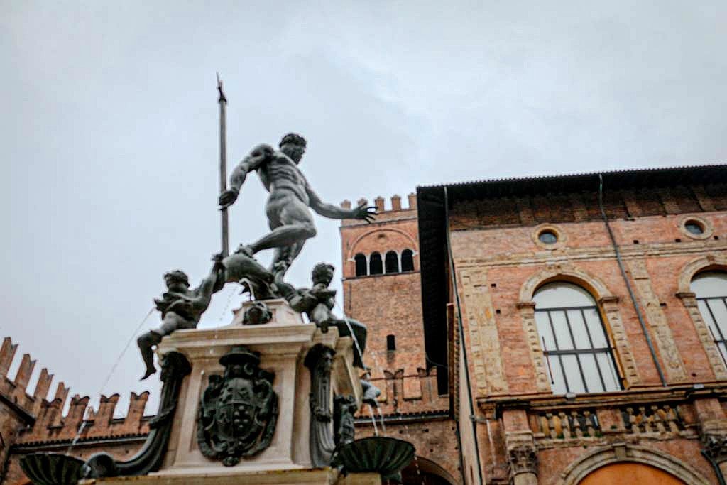Statue of Neptune surrounded by water spouts in a historic European city square.