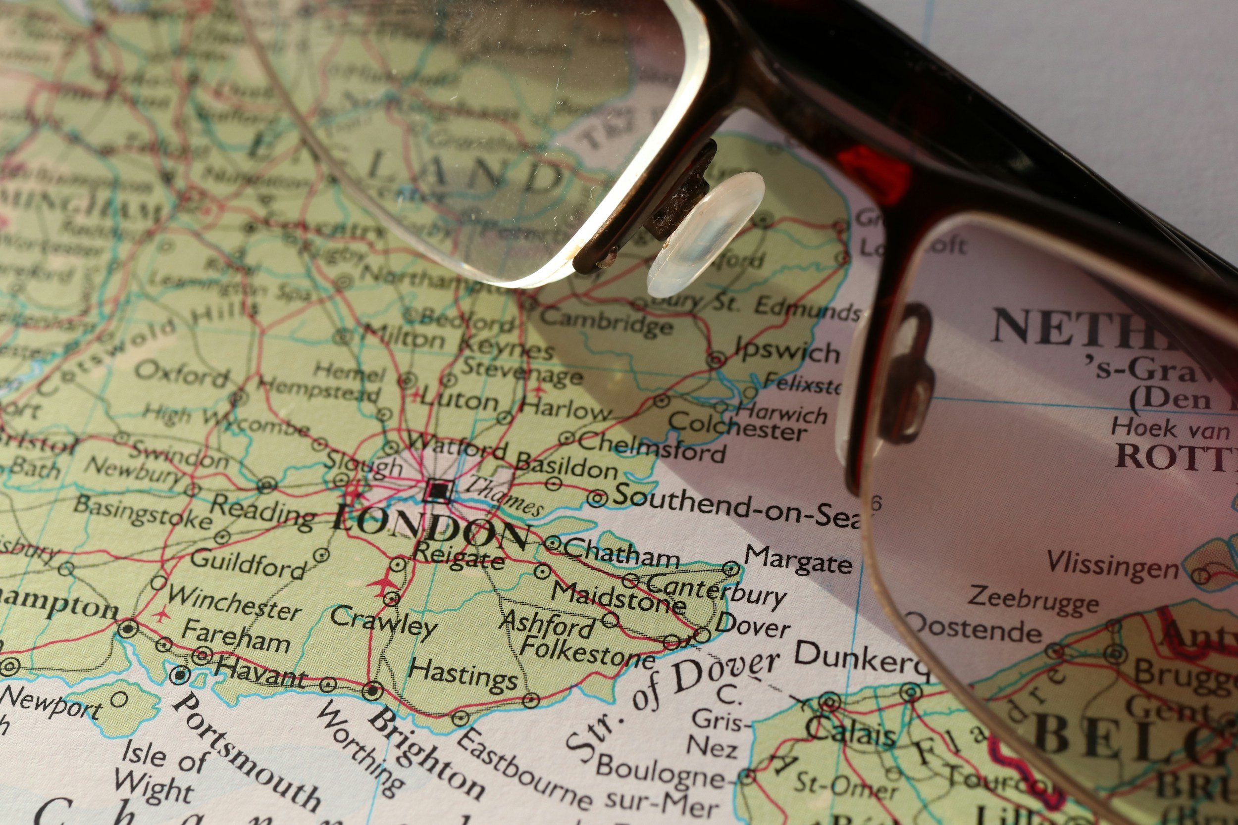 Close-up of a map of southern England, focusing on London and surrounding areas, with a pair of glasses placed on top.