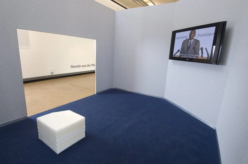 Reaching new frontiers, installation view. Flat-screen monitor, video, sound, wood, metal frame, wallpaper, solution-dyed nylon office carpet, petroleum wax. Installation dimensions variable, 2008