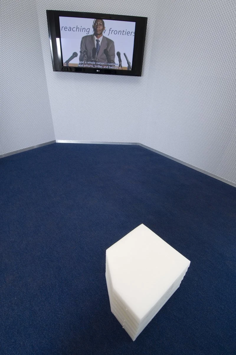 Reaching new frontiers, installation view. Flat-screen monitor, video, sound, wood, metal frame, wallpaper, solution-dyed nylon office carpet, petroleum wax. Installation dimensions variable, 2008
