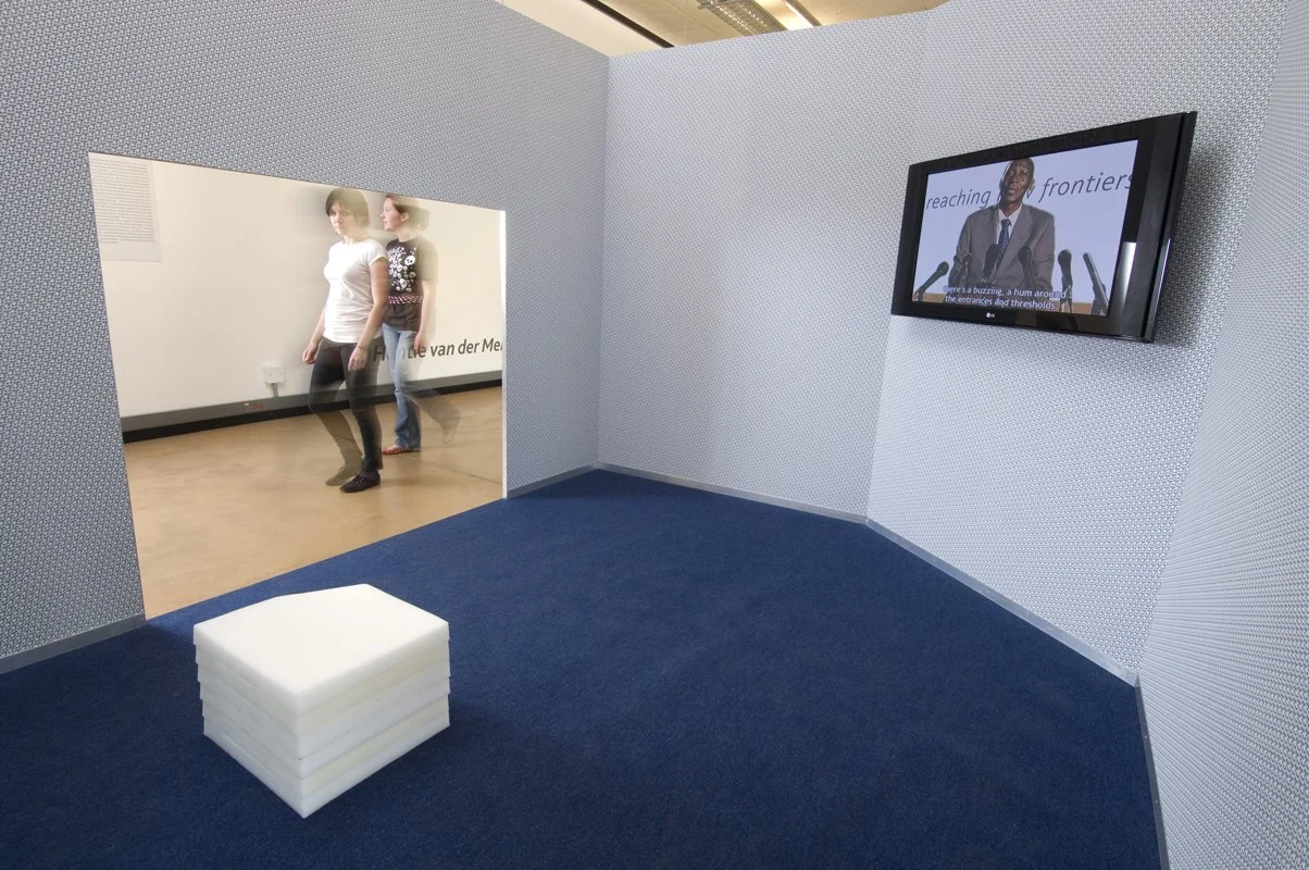 Reaching new frontiers, installation view. Flat-screen monitor, video, sound, wood, metal frame, wallpaper, solution-dyed nylon office carpet, petroleum wax. Installation dimensions variable, 2008