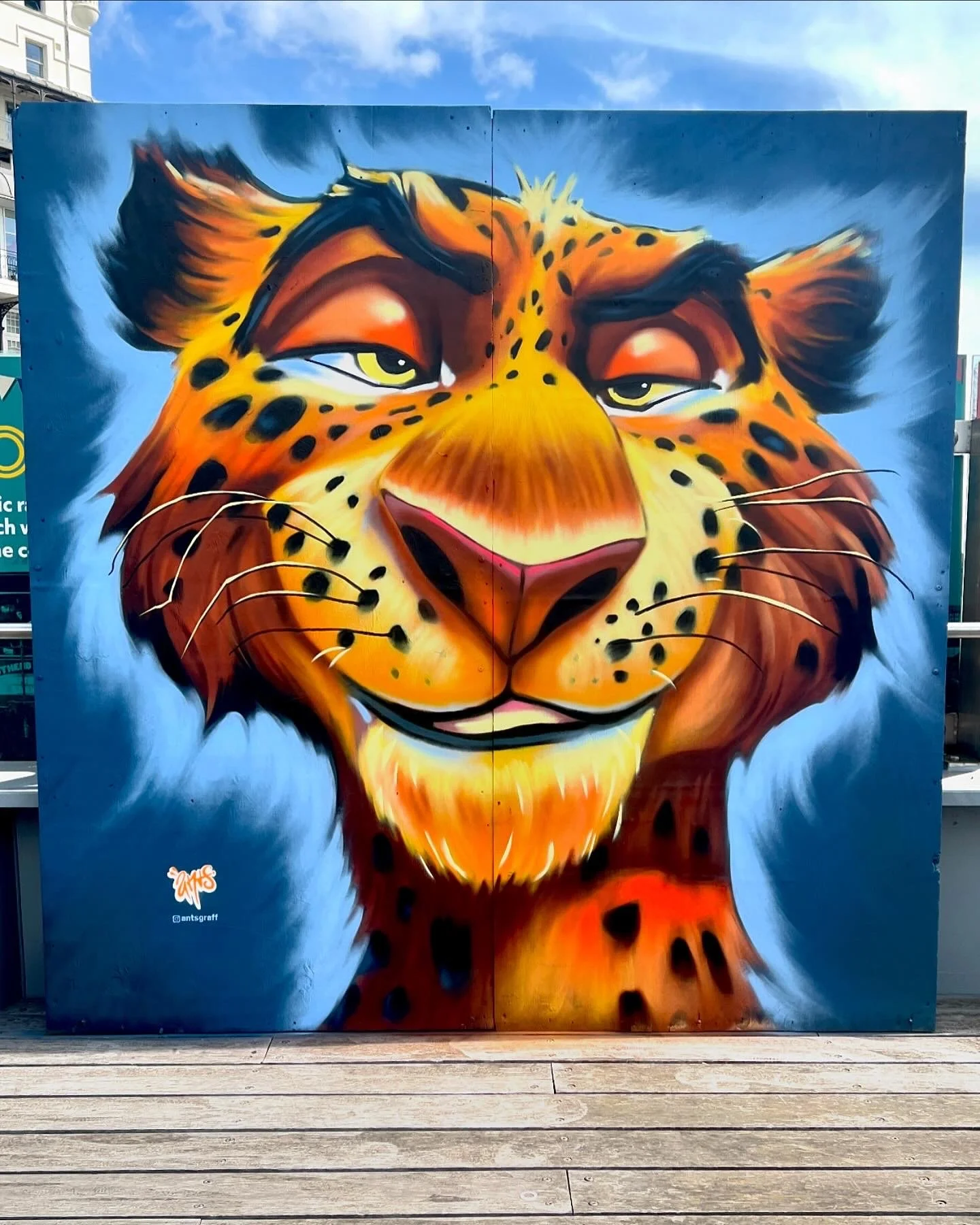 Street art painting of a leopard with a blue background.