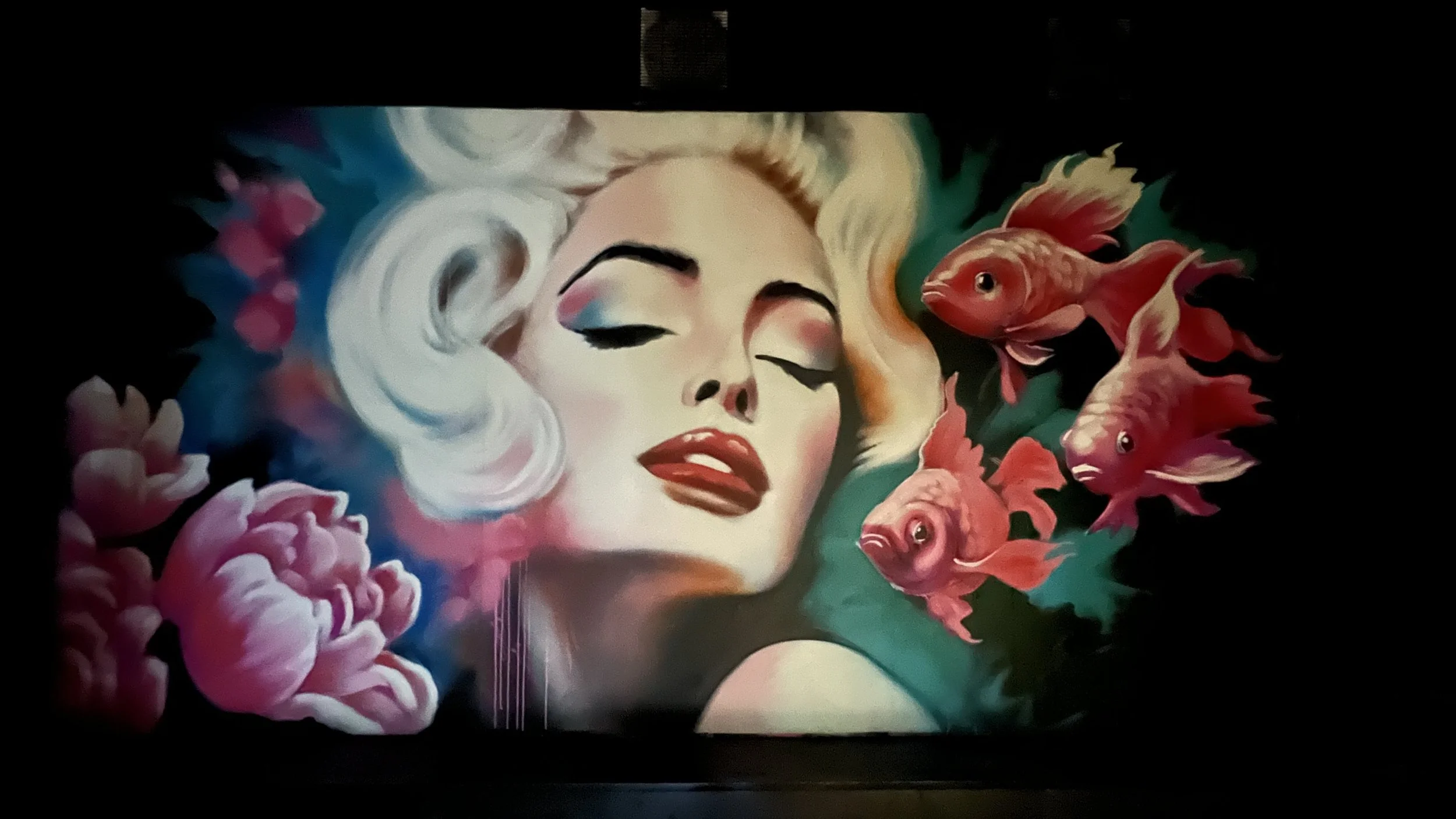 Digital artwork of a woman's face with closed eyes, surrounded by pink flowers and orange koi fish against a dark background.