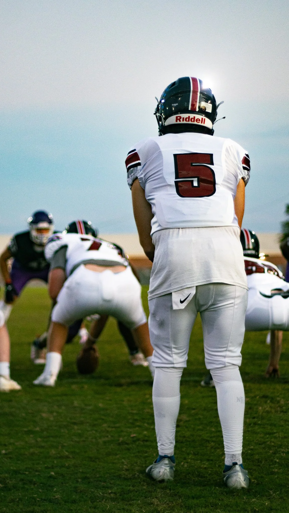 Football player in white jersey with number 5, standing on the field during a game, facing away from the camera, with teammates in the background.