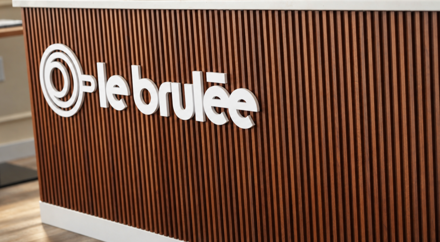 Le Brulée Café logo in white lettering on a wooden café counter.