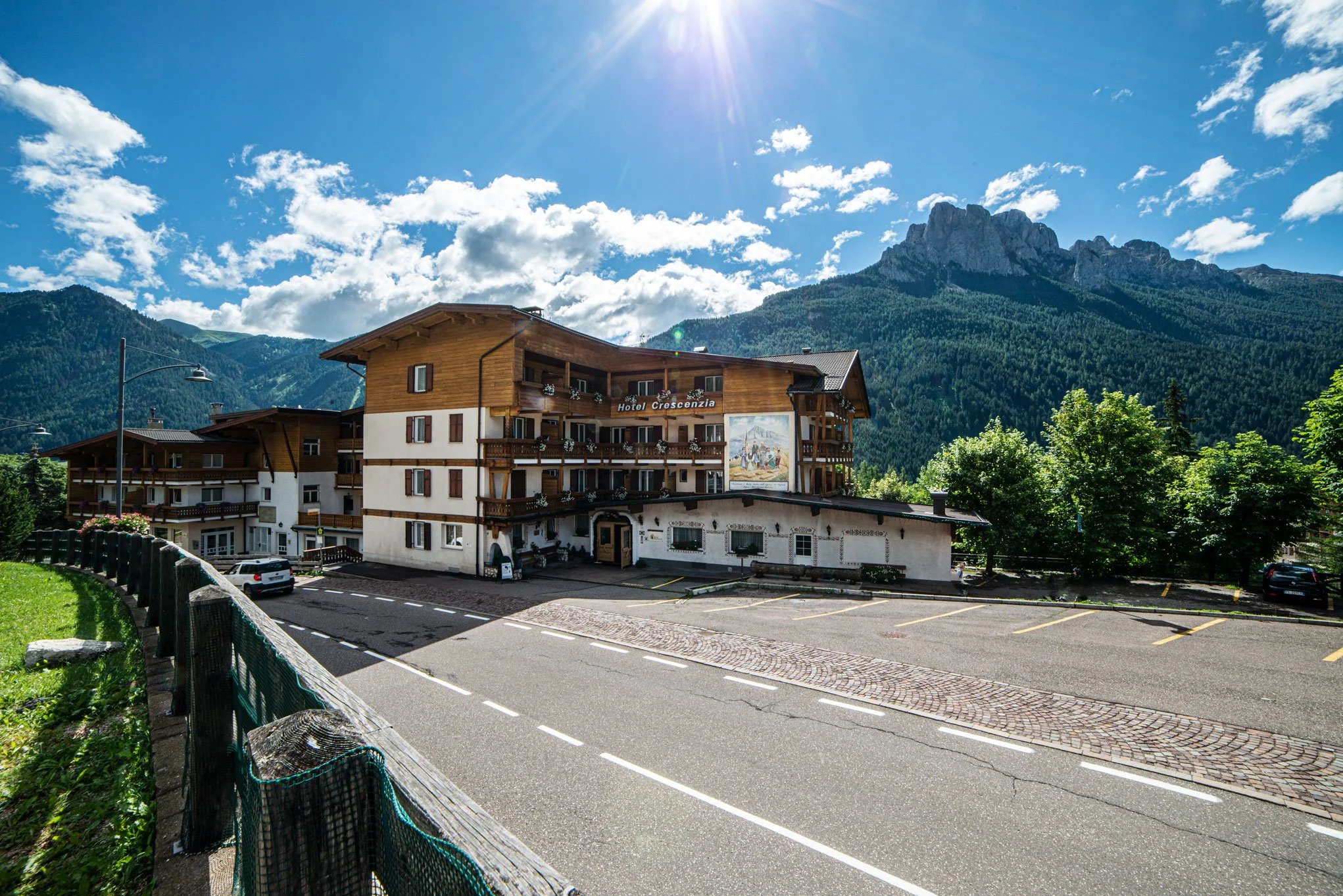 Hotel Crescenzia in una zona montuosa con montagne scoscese sullo sfondo, cielo sereno con alcune nuvole e il sole splendente.