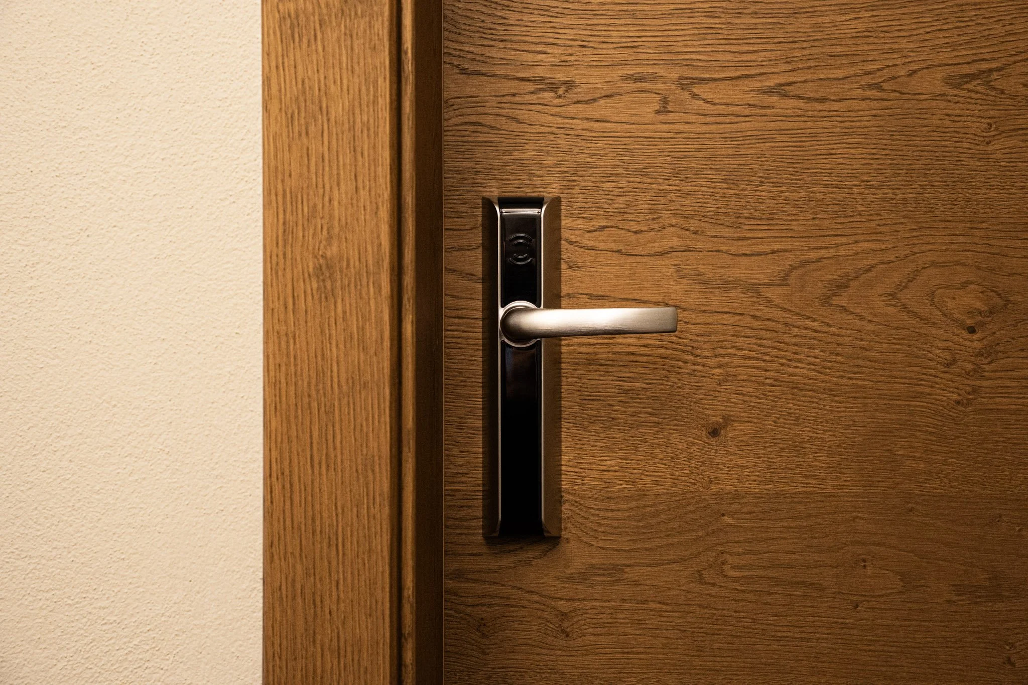 Una porta di legno con manico in metallo e serratura elettronica.