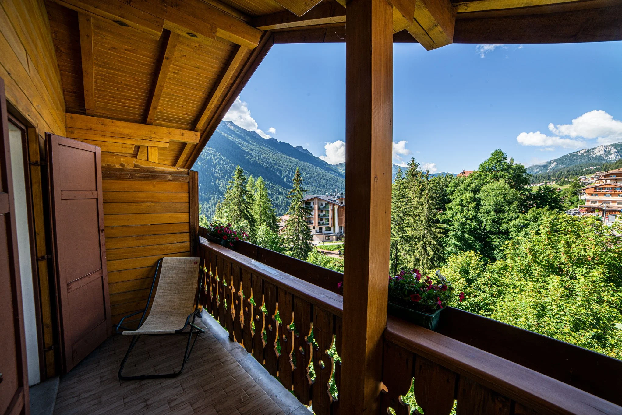 Balcone in legno di una casa con vista sulle montagne verdi e sul cielo blu