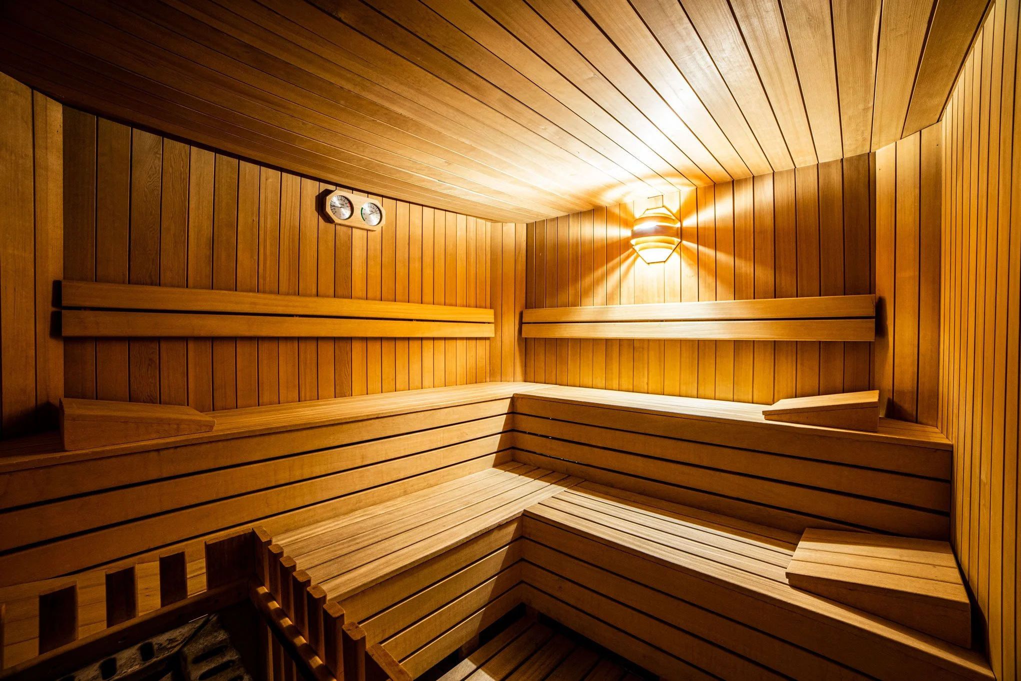 Interno di una sauna di legno con sedili a livelli e illuminazione soffusa.