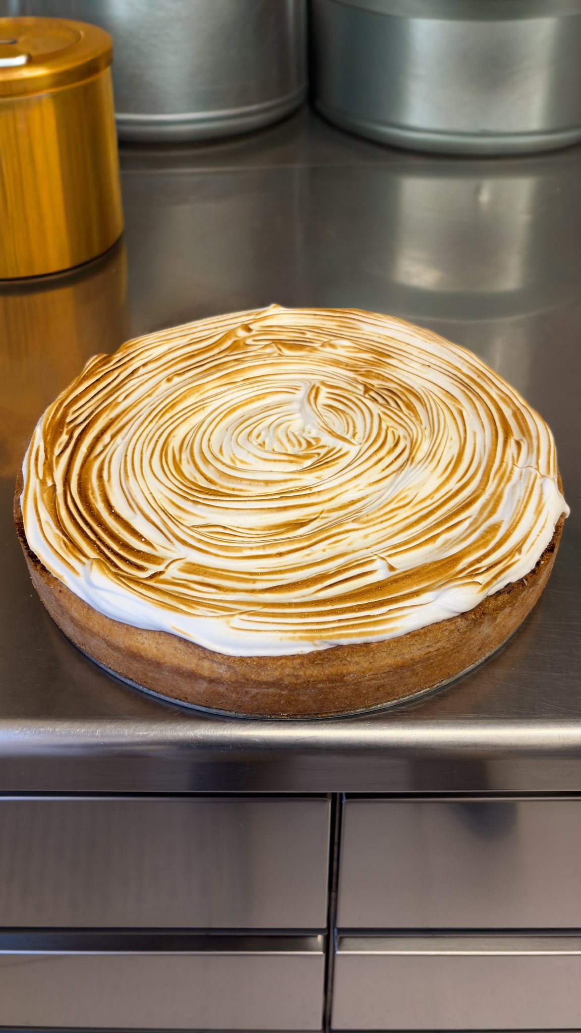 Torta con decorazione di cioccolato e meringa in un ambiente da cucina.