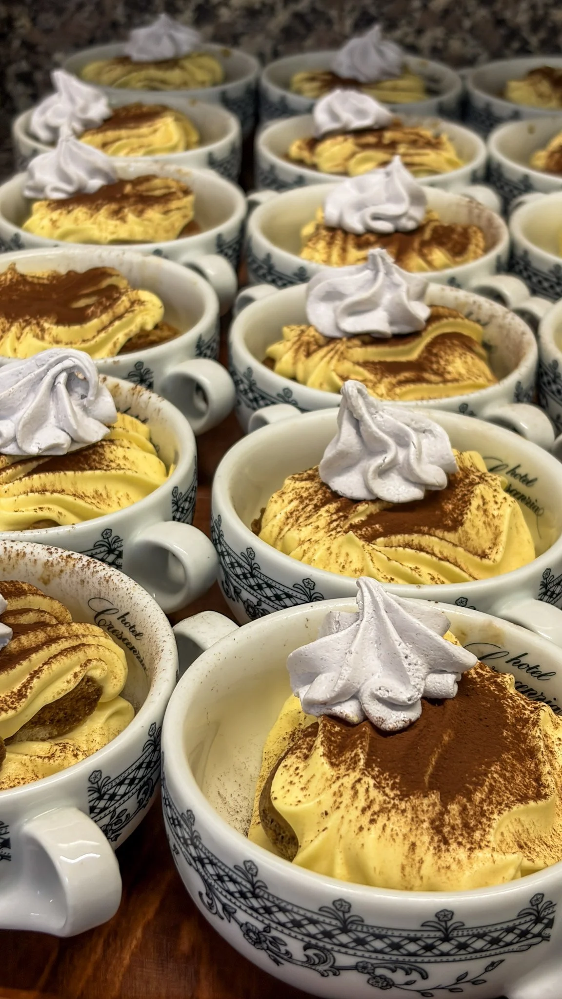 Ciotole di tiramisù decorato con cacao in polvere e panna montata.