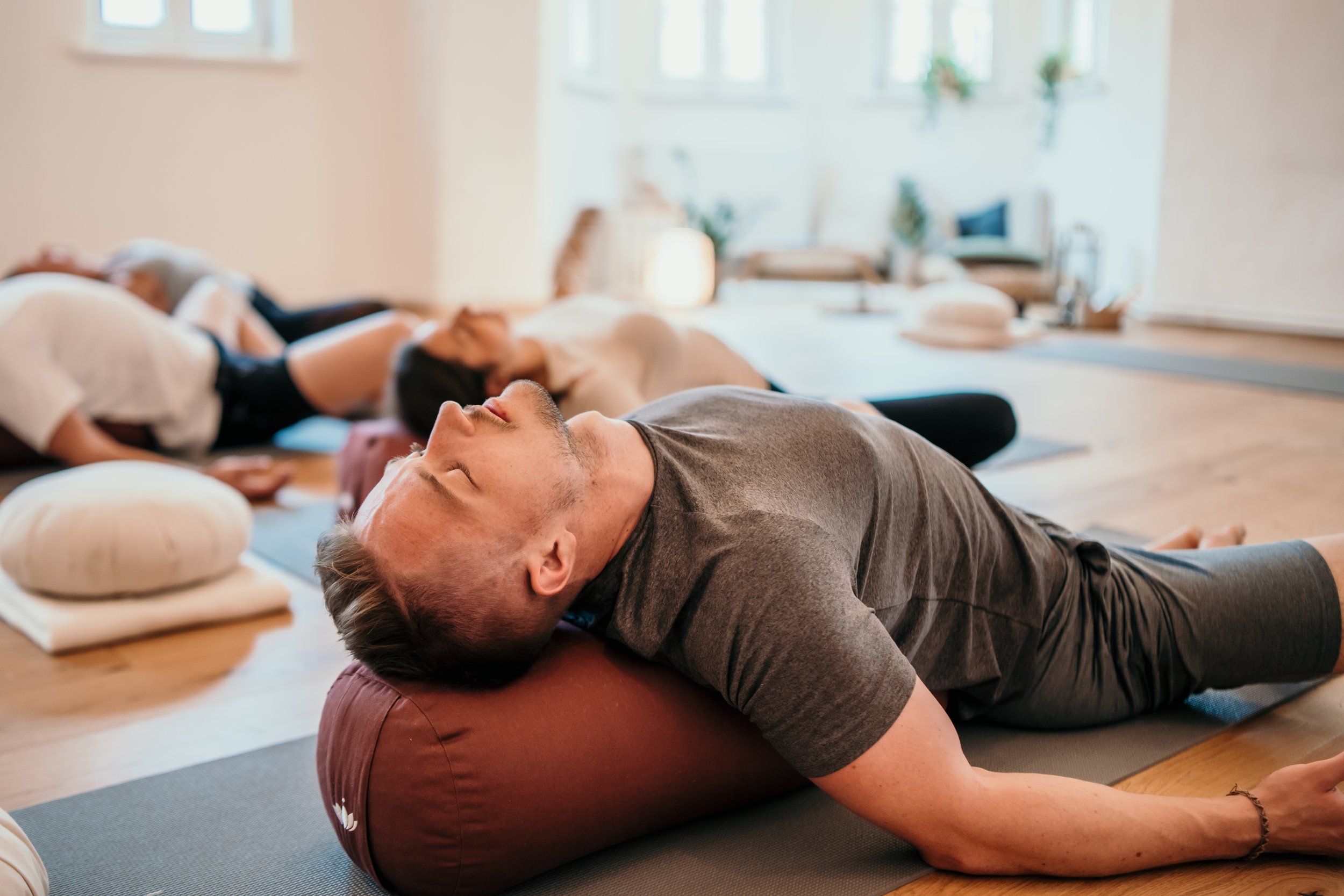 Menschen, die im Yoga-Raum liegen und an einem Yoga-Kurs teilnehmen.
