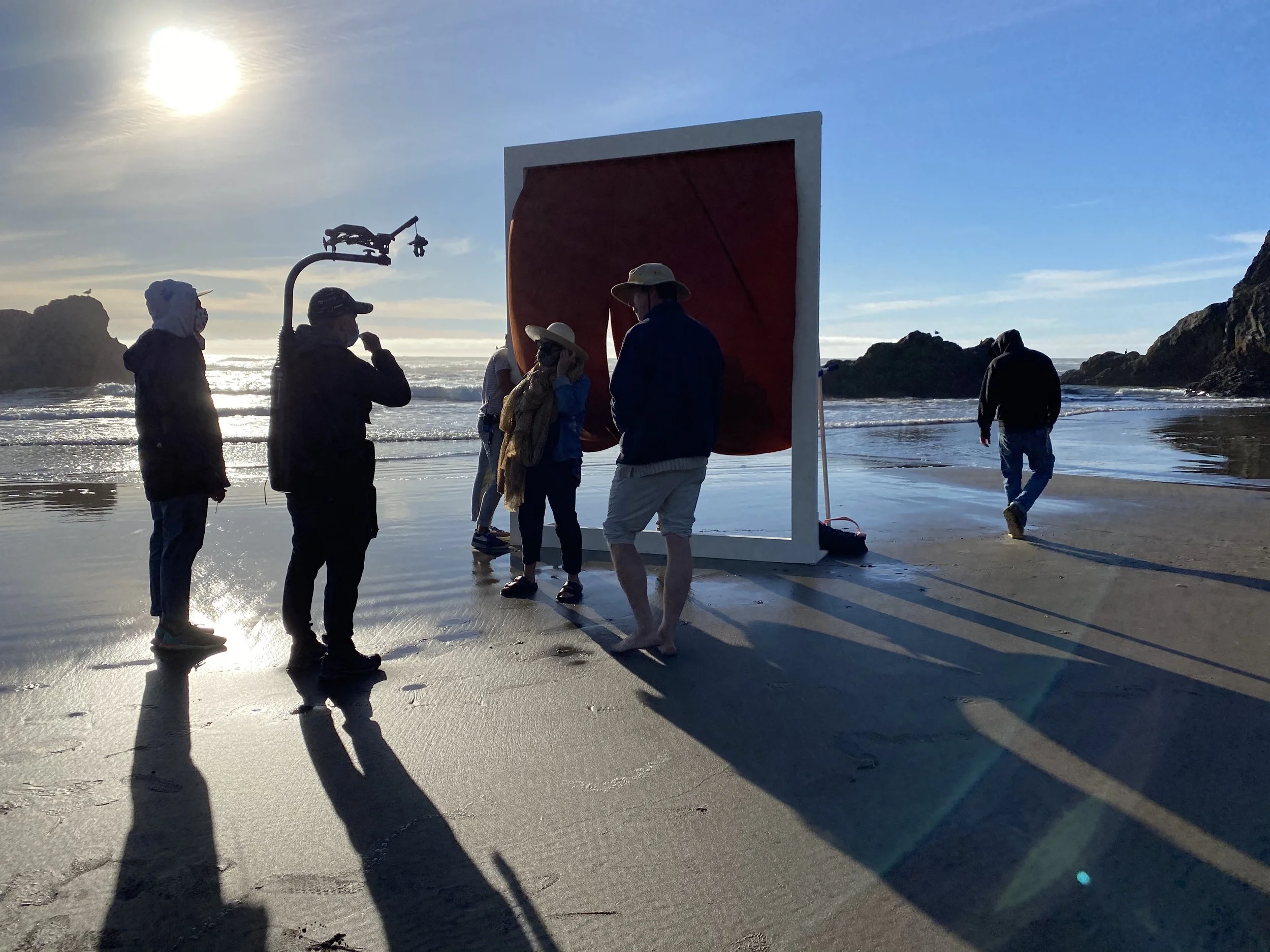 Behind-the-scenes production image from Bright Black’s Nike Latinx shoot at Cannon Beach, Oregon, with crew setting a constructed frame in the surf at magic hour.
