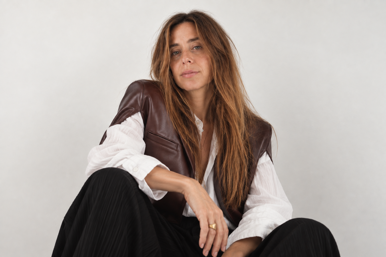 Editorial portrait of Brooke McDaniel in a white blouse, brown leather vest and black trousers.