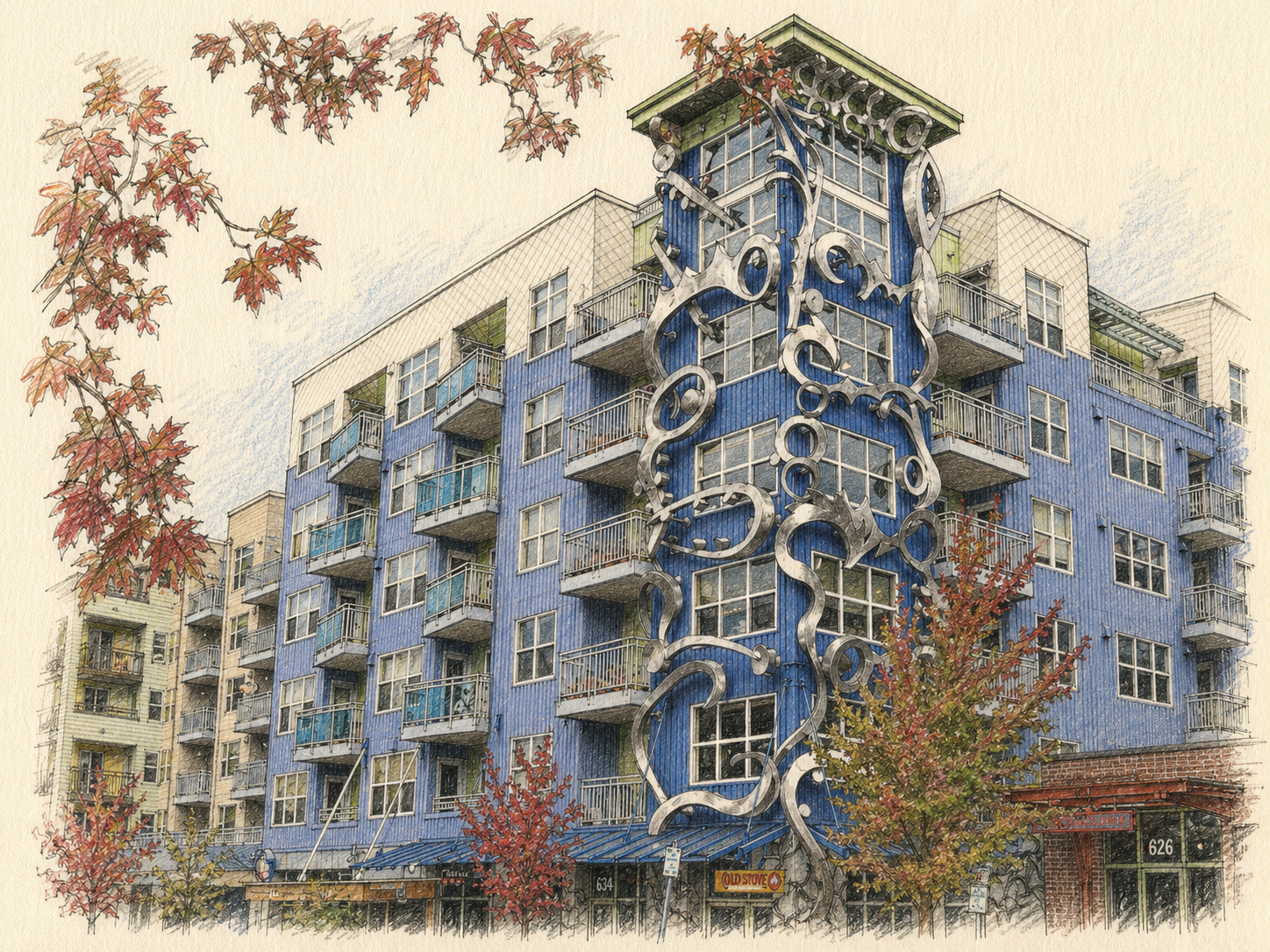 A colorful building painted in blue with a decorative metal sculpture on its facade, featuring balconies and multiple windows, surrounded by trees with autumn leaves.