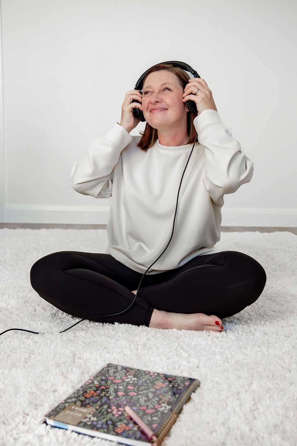 Liz Chapman in her office sitting on the floor with headphones on smiling