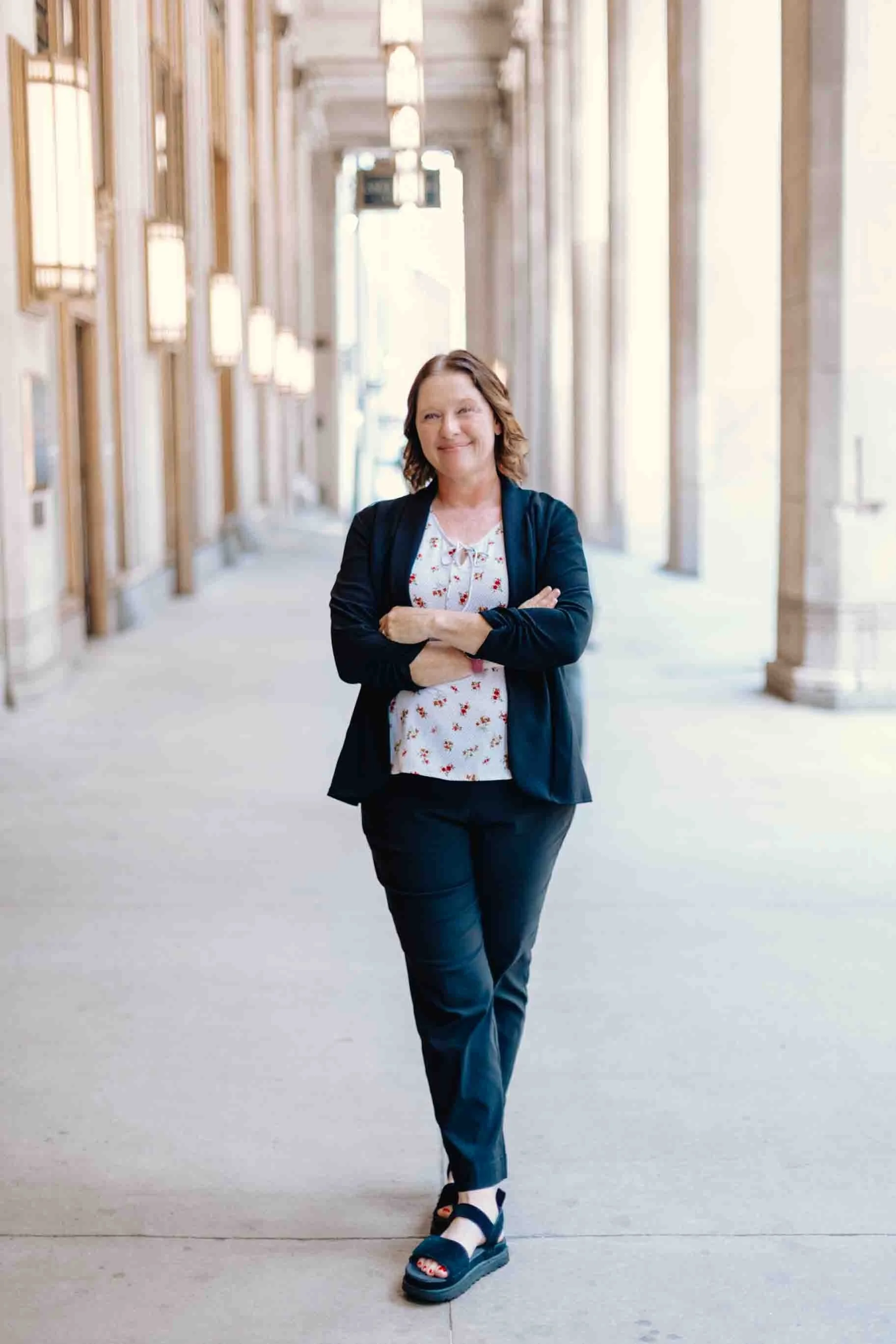 Liz chapman, podcast strategist, standing outside in downtown Chicago, smiling at the camera with her arms crossed