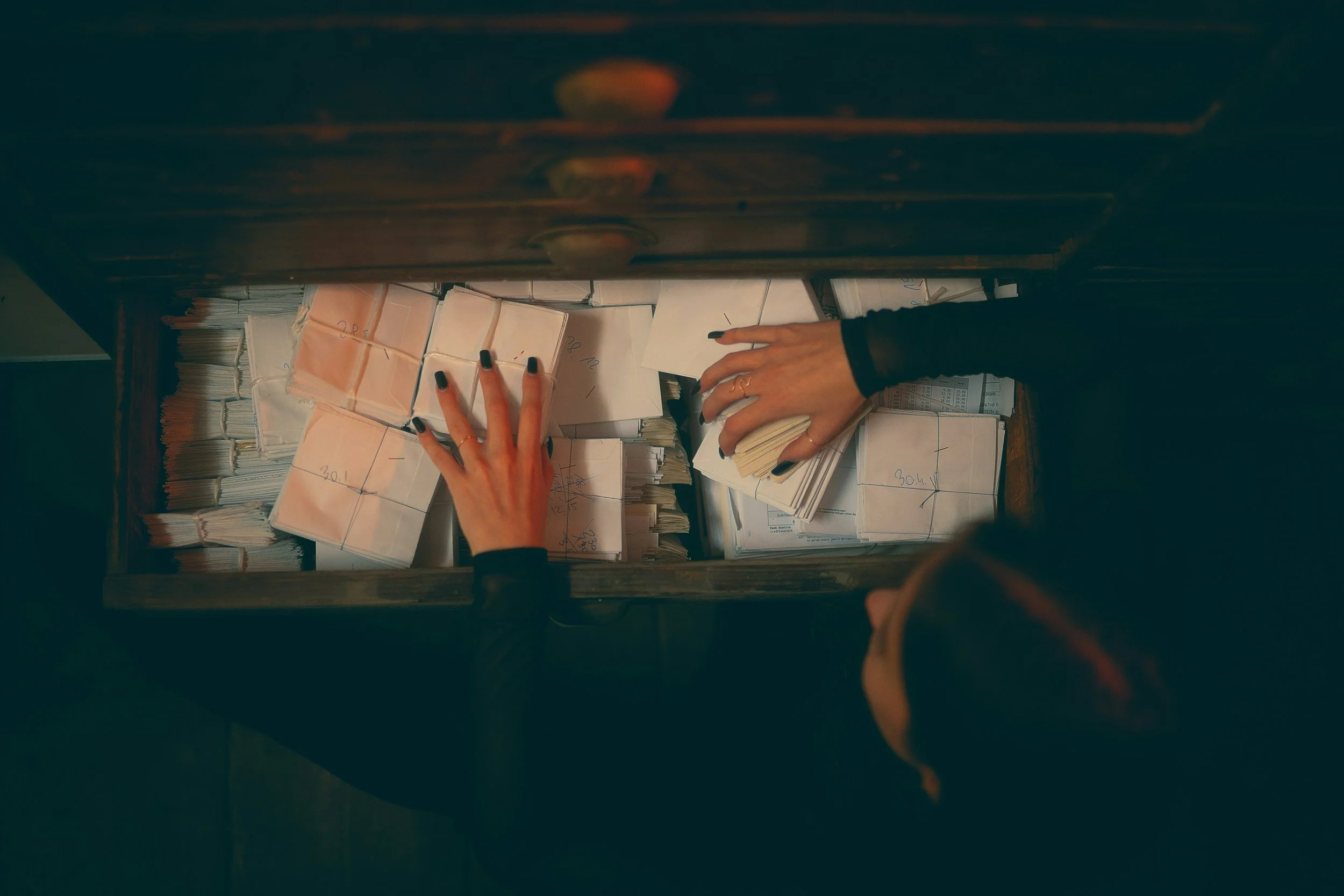 A woman is looking through a drawer filled with papers.
