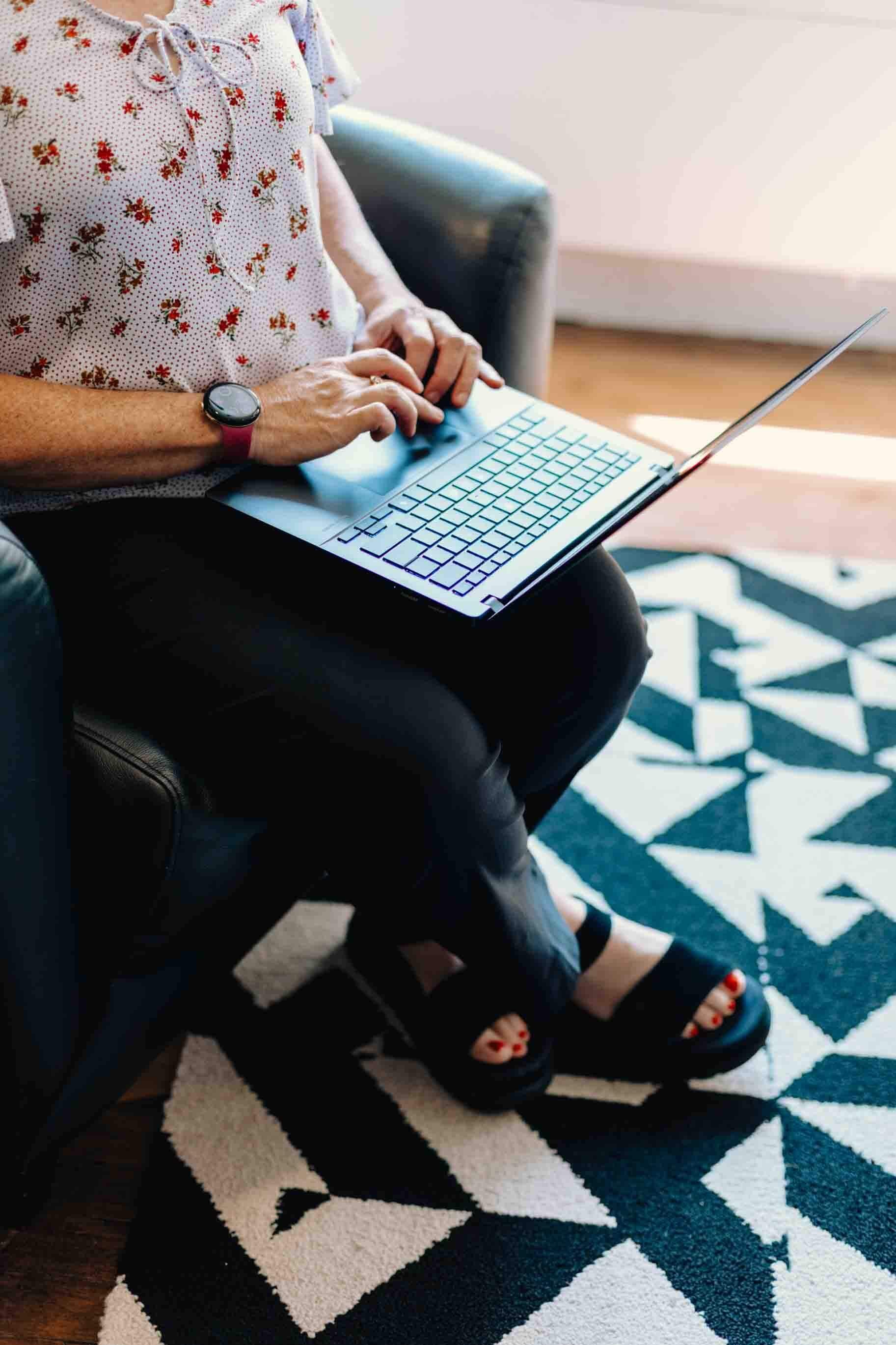 Liz chapman sitting in a chair and is typing on her laptop