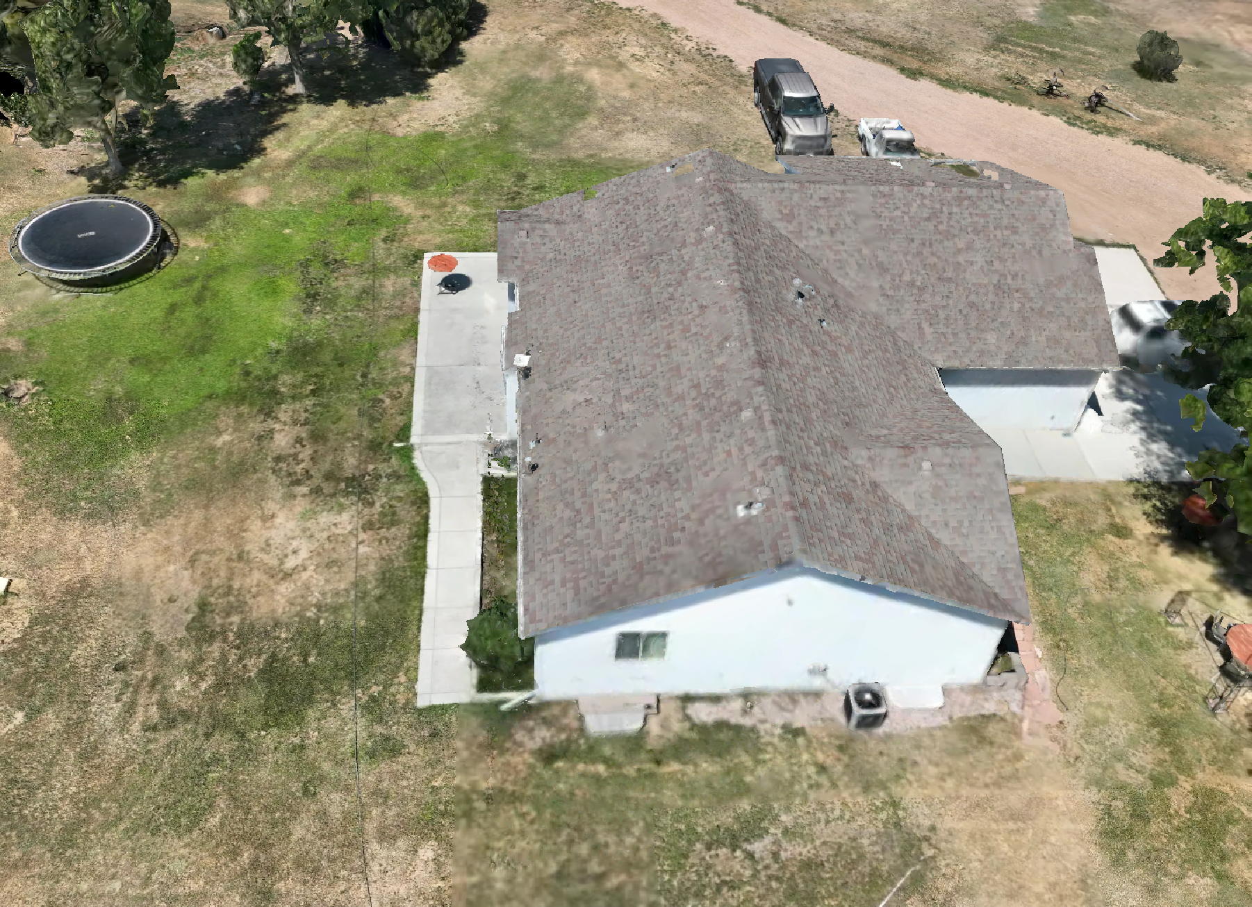 An aerial view of a house with a tiled roof, a concrete sidewalk, and a backyard with a trampoline, a pig statue, and some trees.