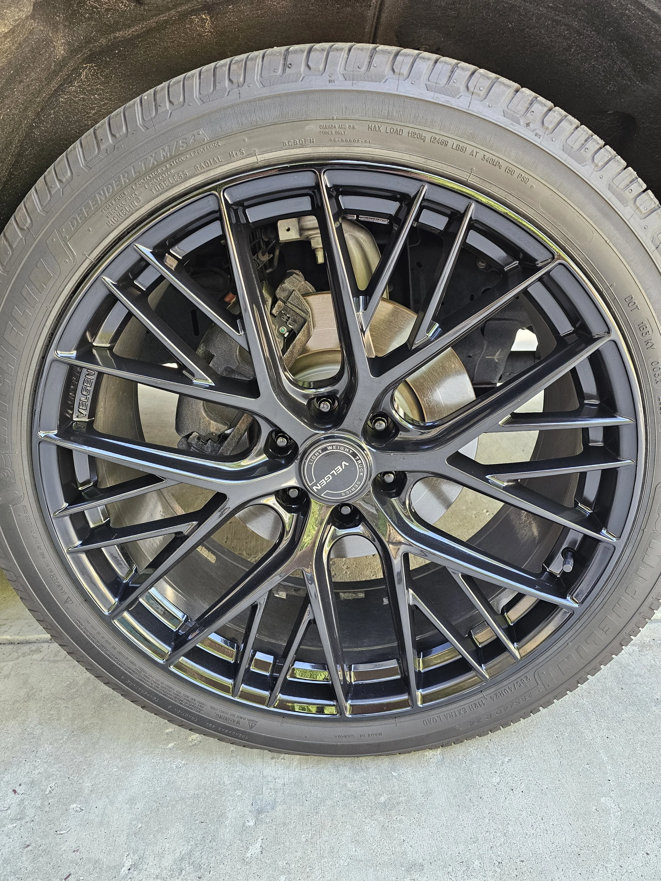Close-up of a car tire with a refinished black alloy wheel.