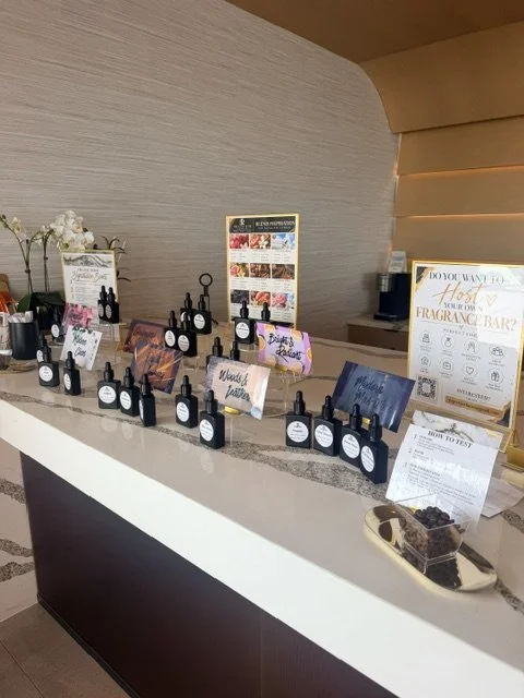 A display counter with various small bottles, informational signs, and promotional materials for a fragrance or essential oil bar