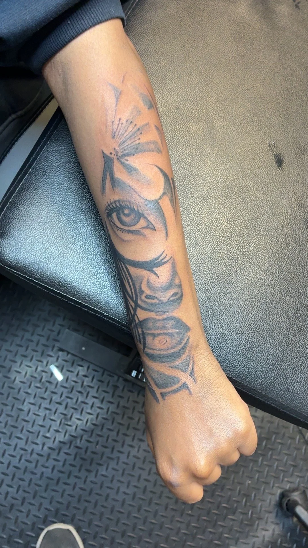 Tattoo of a woman's eye, nose, and lips with a butterfly over the eye, on a person's forearm.