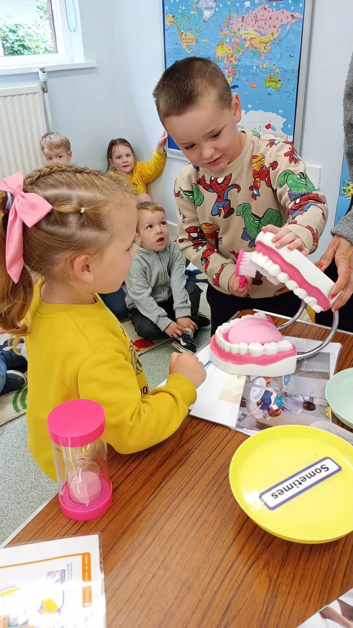 Children attending a classroom activity with a dental model to teach about teeth.