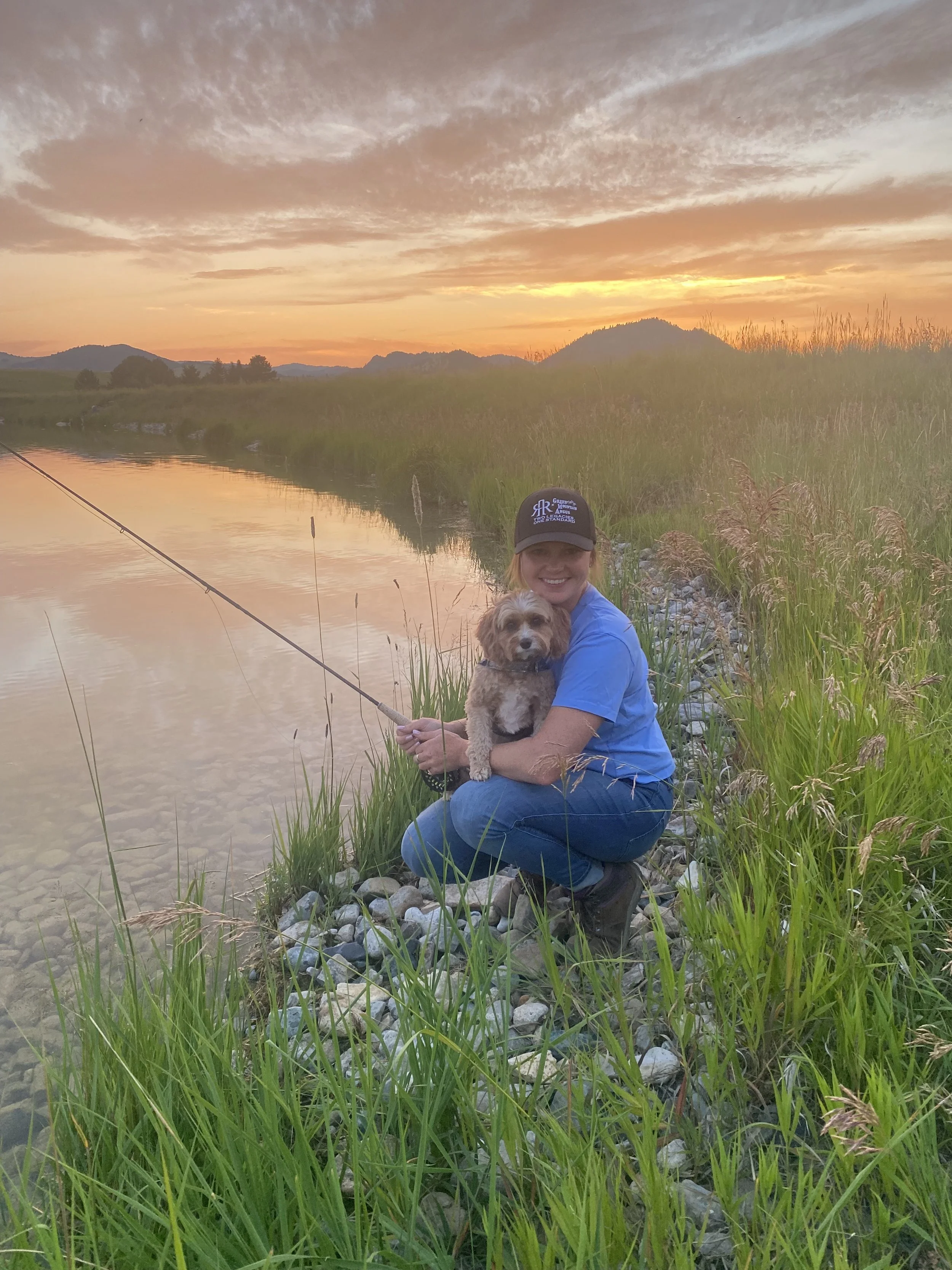 Hannah and her cavapoo, Shandy fly fishing at sunset in the Montana mountains.