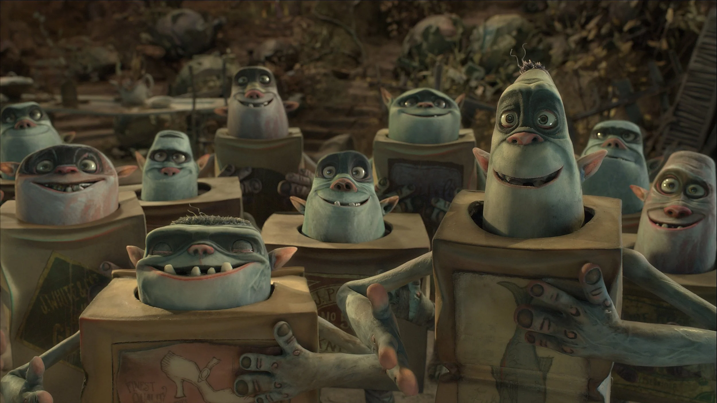 Multiple animated goblin-like creatures with green skin and distinctive facial features inside cardboard boxes, set against a dark, cluttered background.