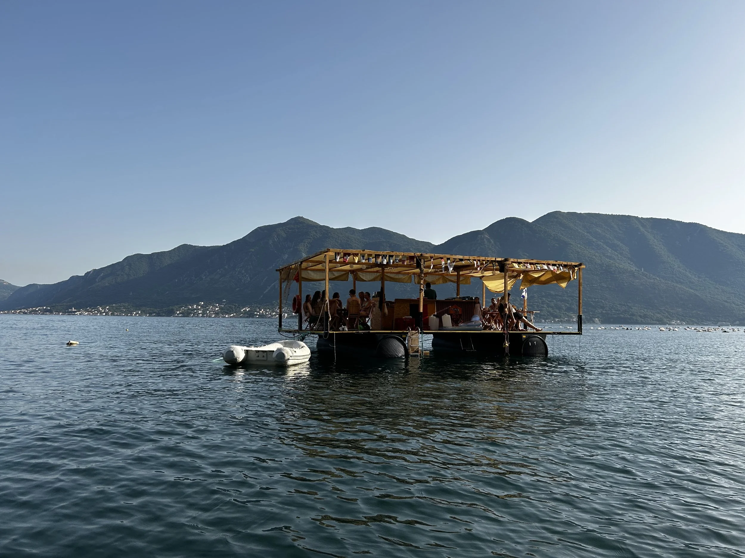 A group of people sitting on a floating wine bar in the ocean in Montenegro.