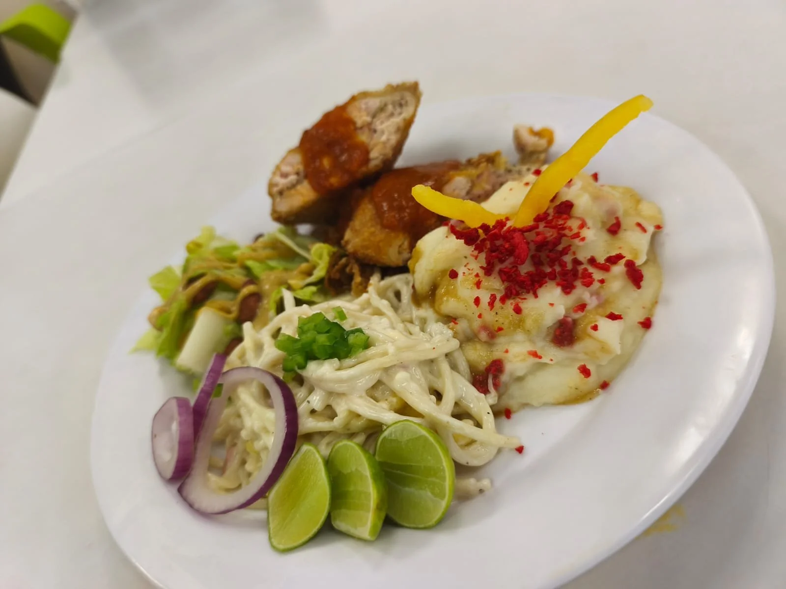 Plato con ensalada, pollo con salsa y puré de papa con aderezo