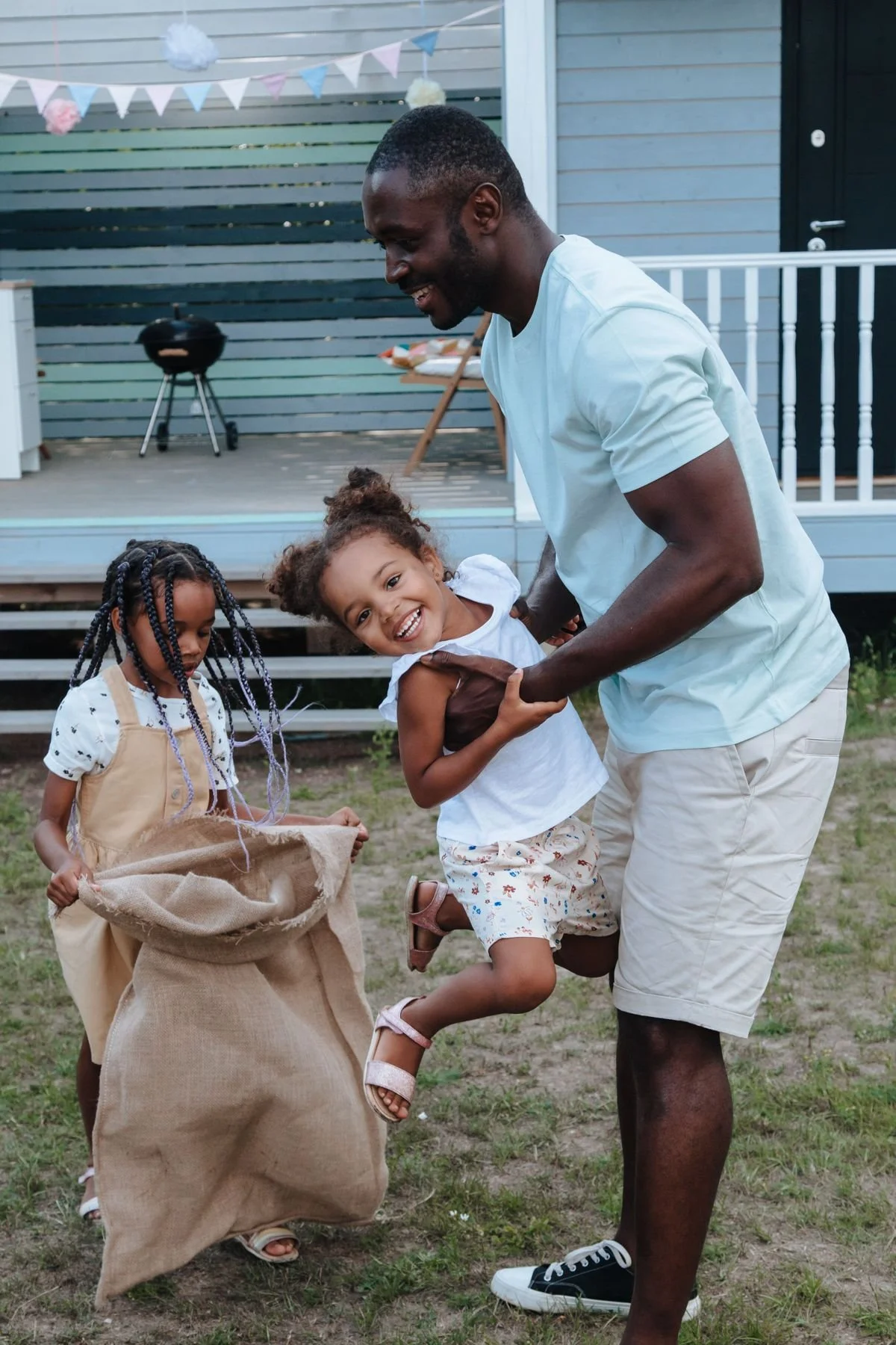 A dad playing with his daughters in the backyard